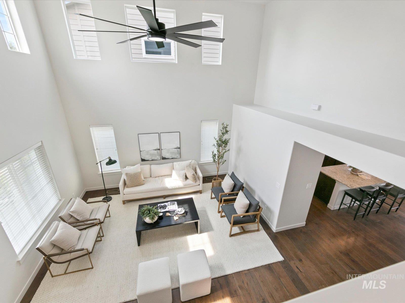 Living room featuring a high ceiling, wood finished floors, and ceiling fan