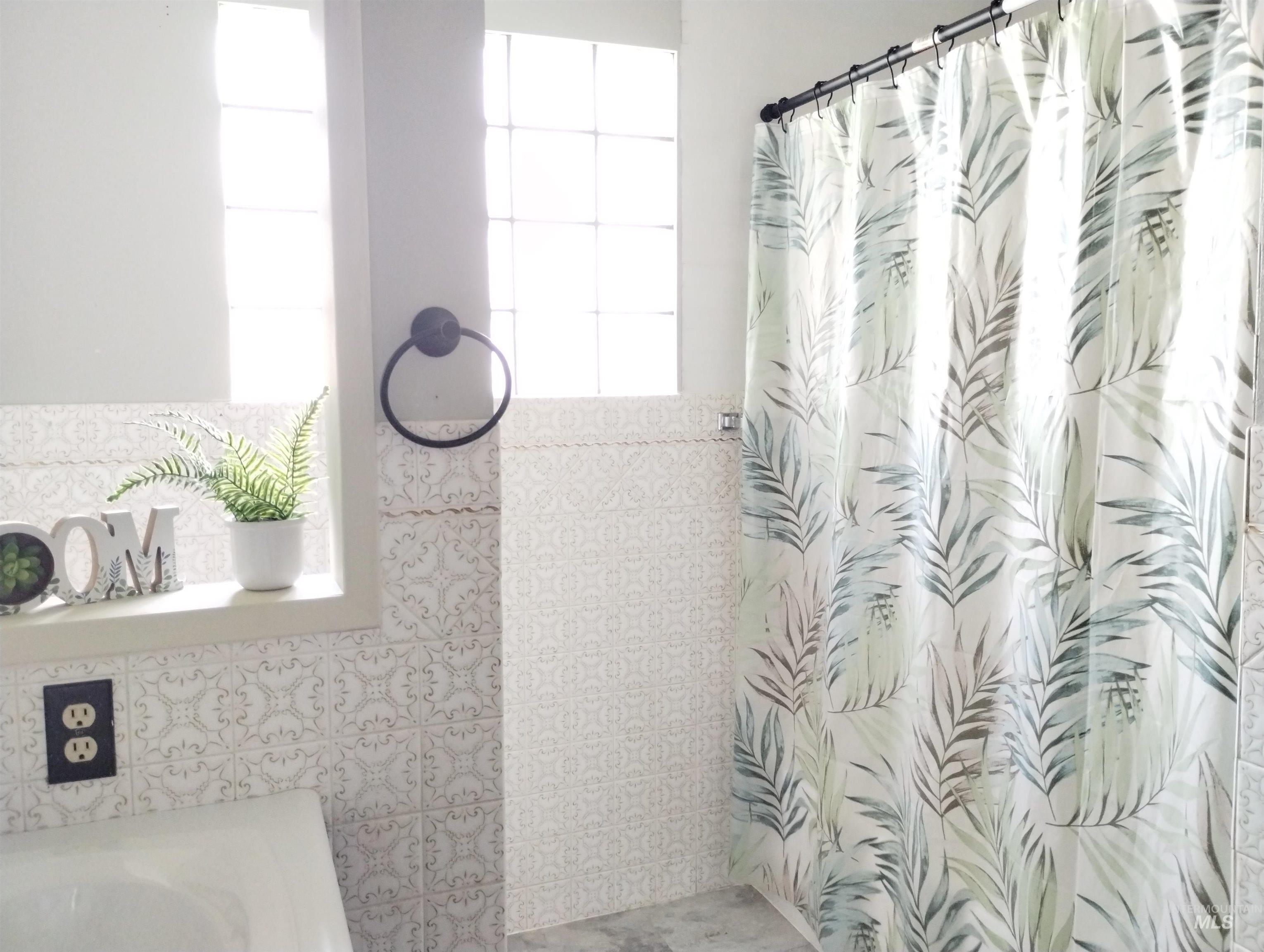 Full bathroom featuring tile walls and curtained shower