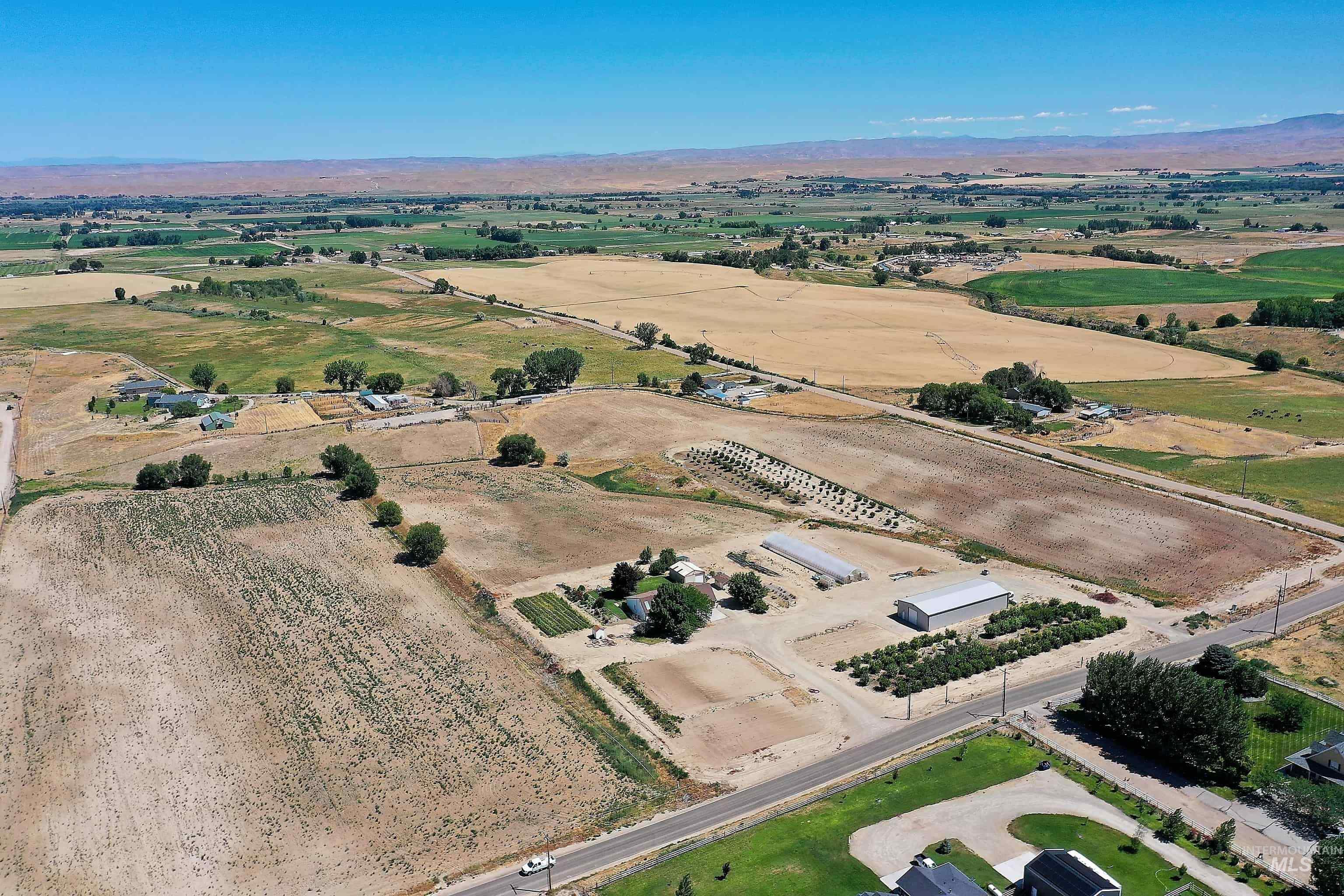 Aerial view of property's location featuring rural landscape, a mountainous background, and rows of crops
