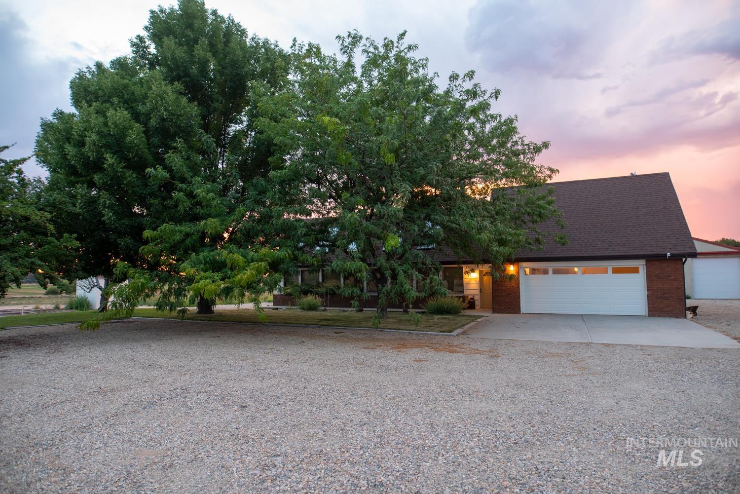 View of front of house featuring driveway, a shingled roof, brick siding, and a garage