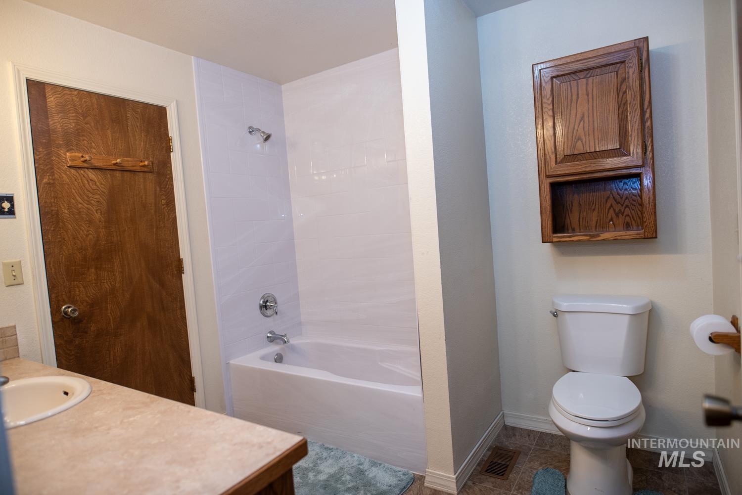 Full bathroom with washtub / shower combination, vanity, and dark tile patterned flooring