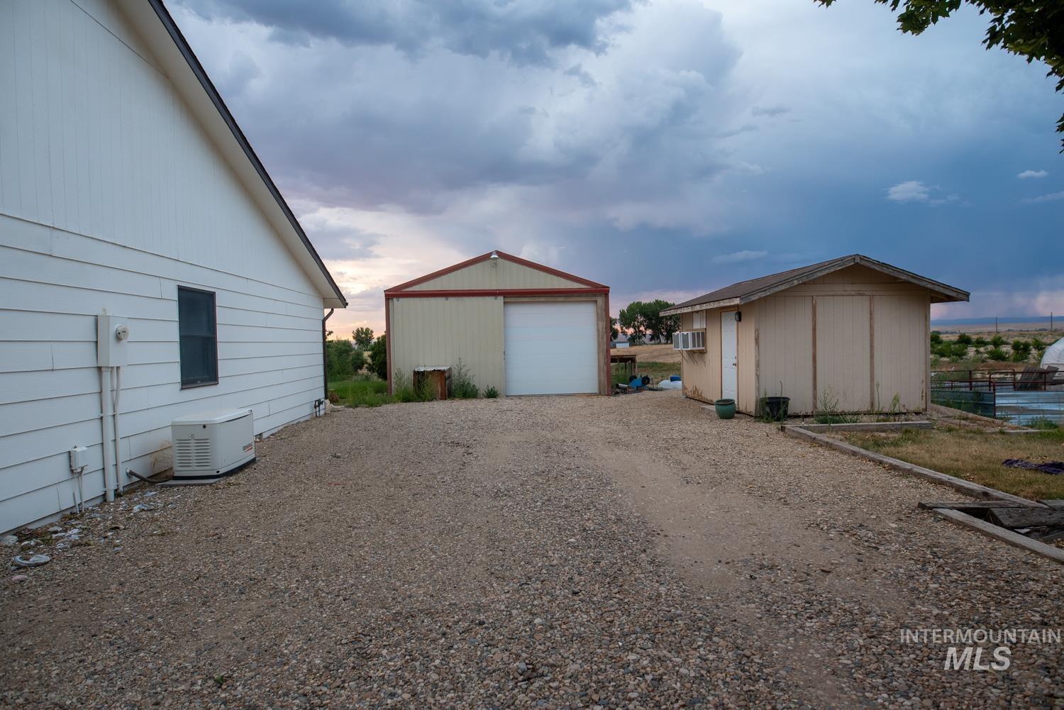 Property exterior at dusk with an outbuilding, a garage, and gravel driveway