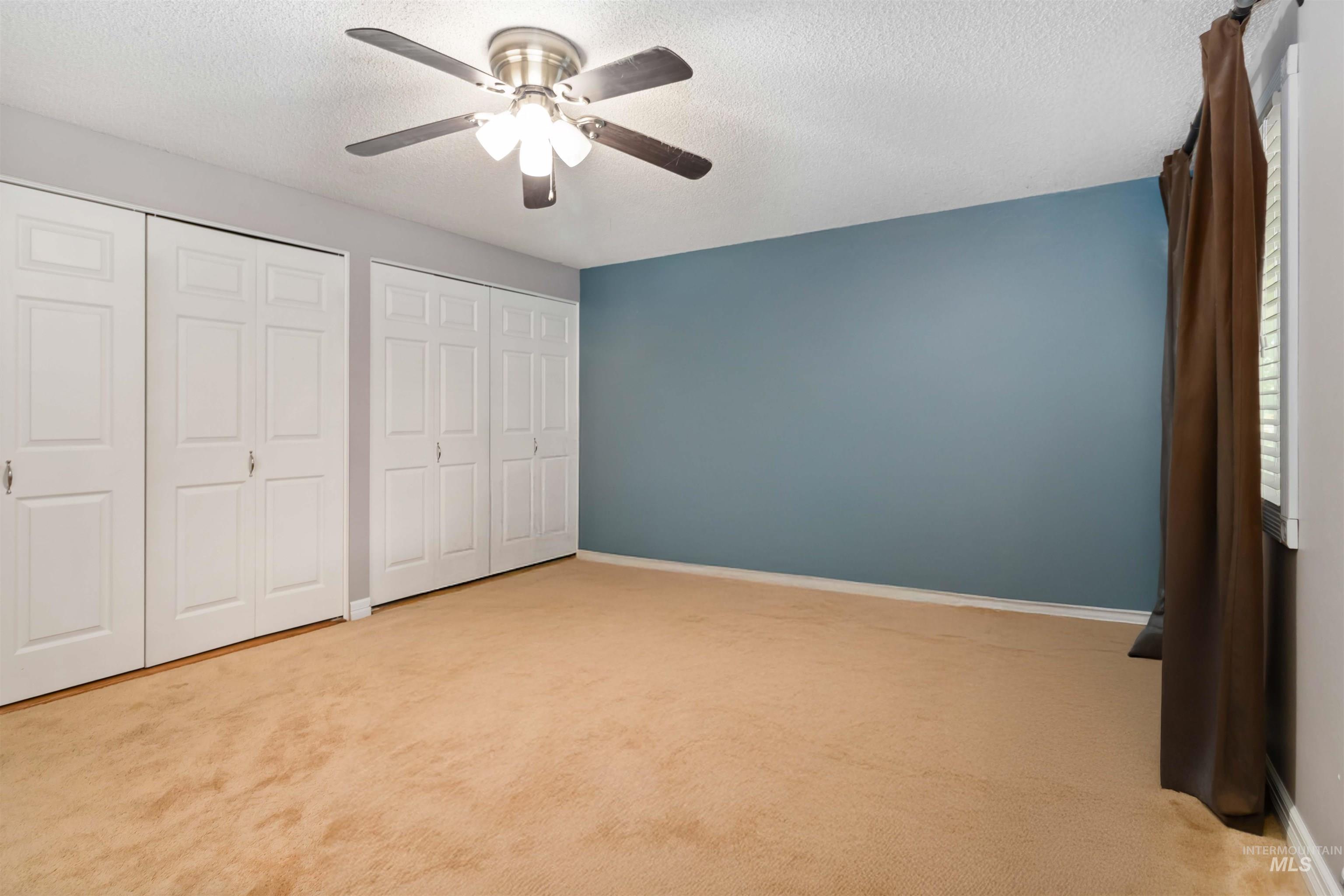 Digitally Unfurnished bedroom featuring double closets, carpet  and a ceiling fan.