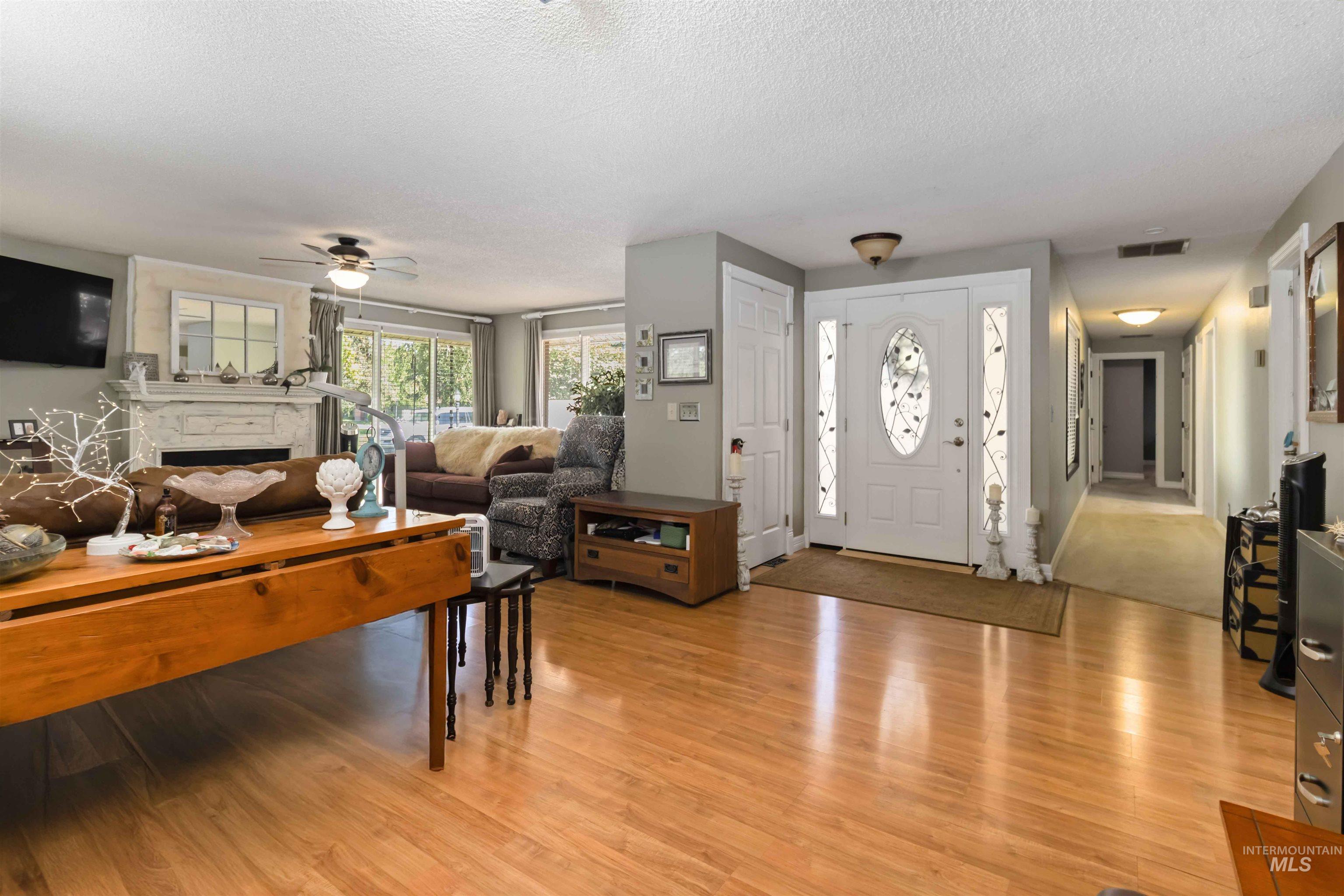 Entryway featuring a textured ceiling, light wood-style floors, a fireplace, and ceiling fan