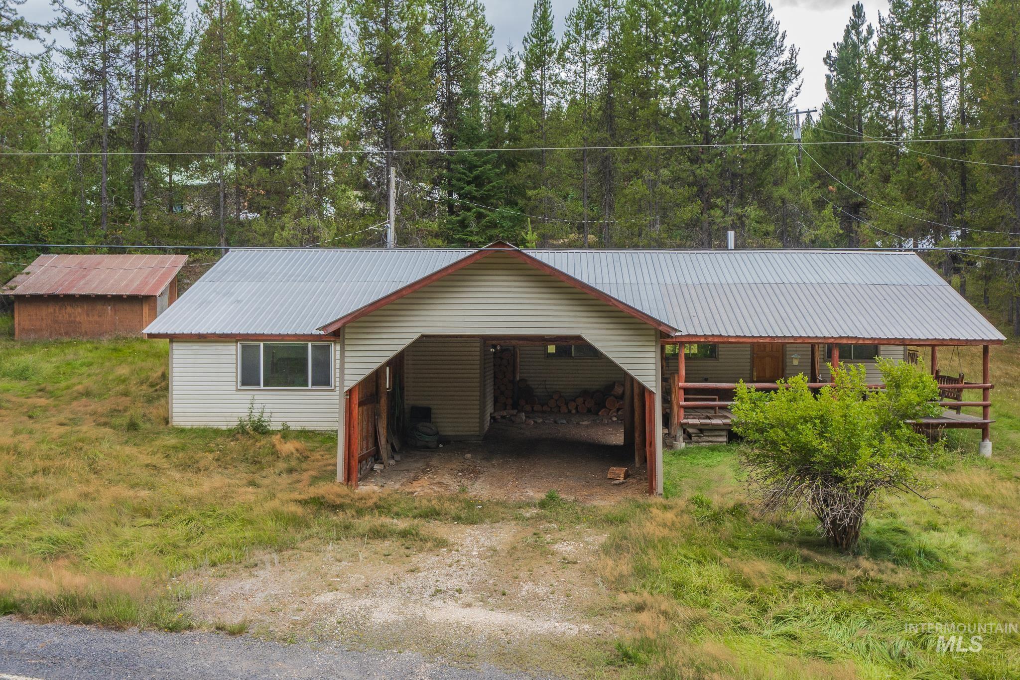 View of front of house featuring a metal roof, a carport, driveway, and view of wooded area