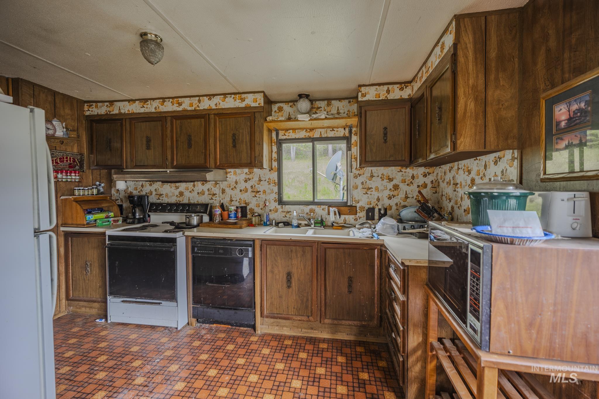 Kitchen featuring light countertops, white appliances, dark floors, and dark brown cabinetry