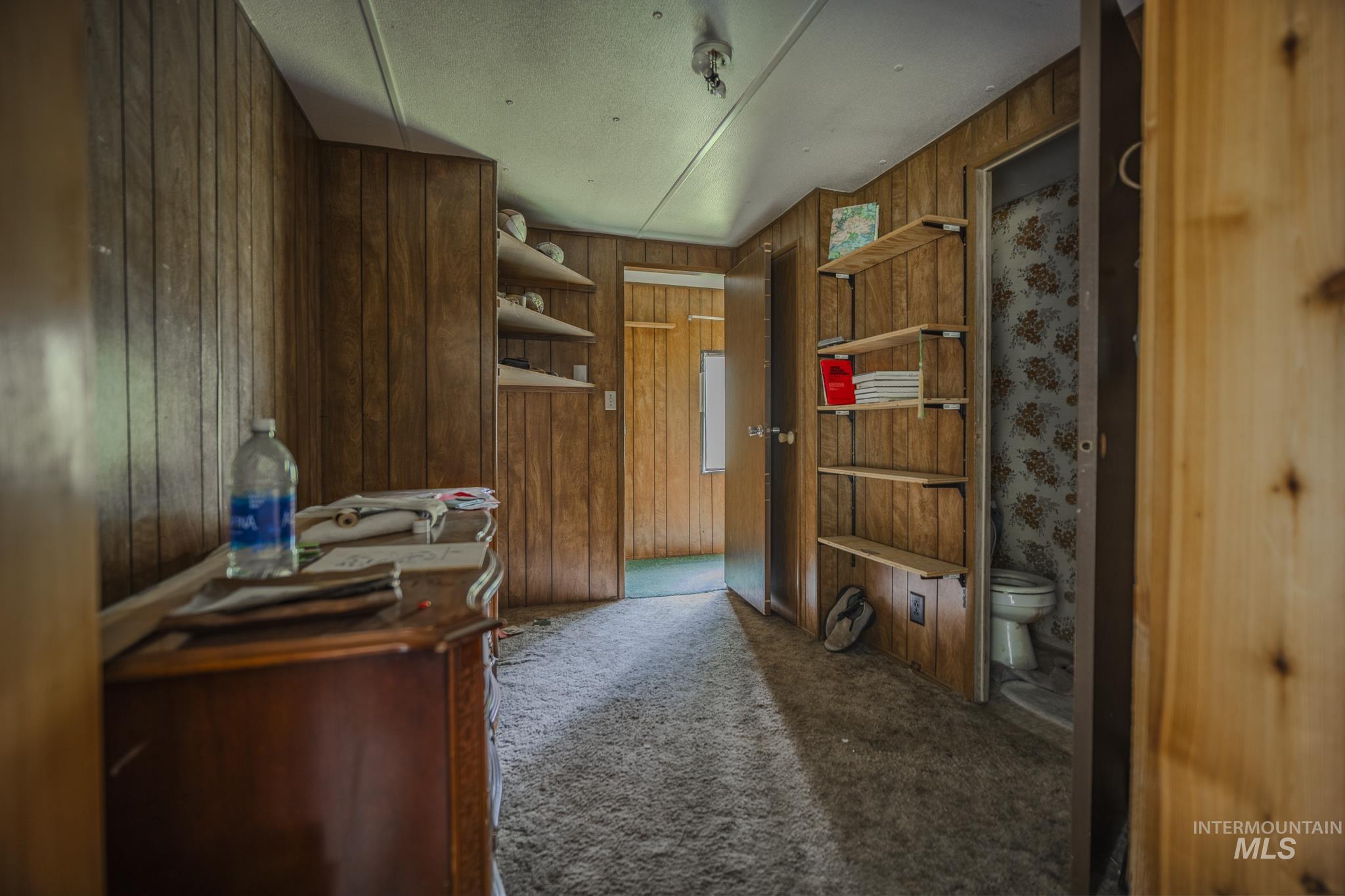 Home office featuring carpet floors and wooden walls