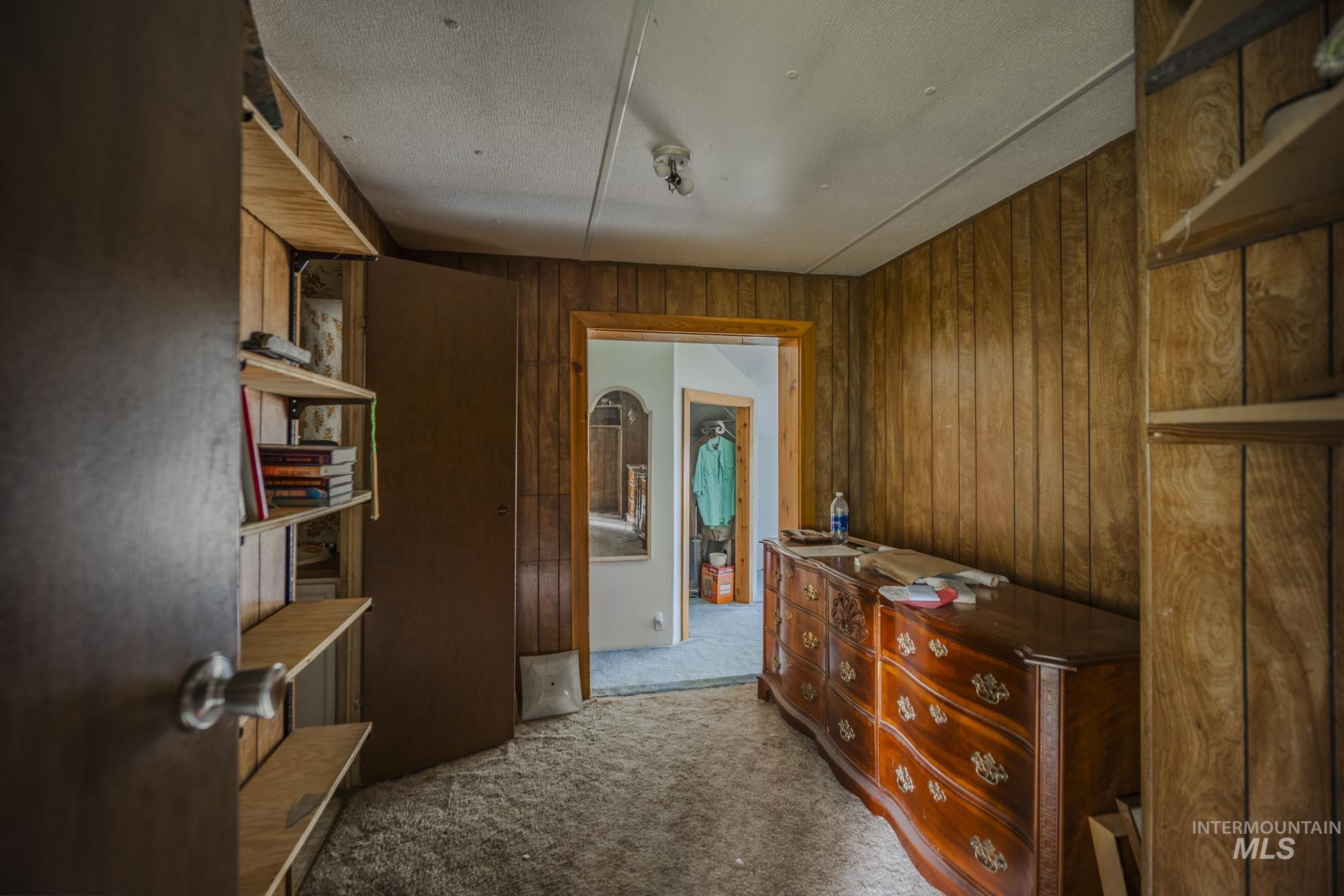 Corridor with light colored carpet, wooden walls, and a textured ceiling