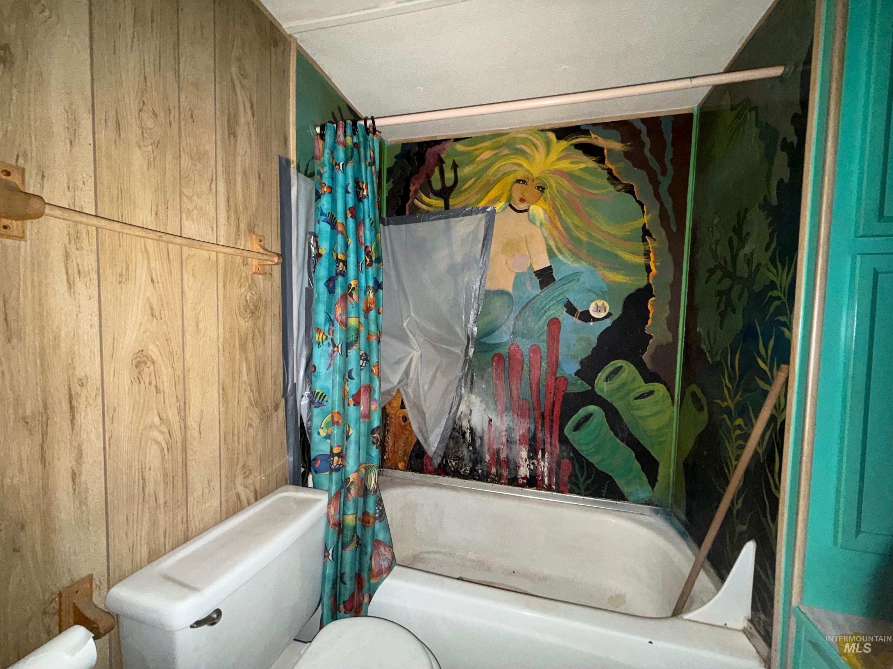 Bathroom featuring wooden walls and shower / tub combo