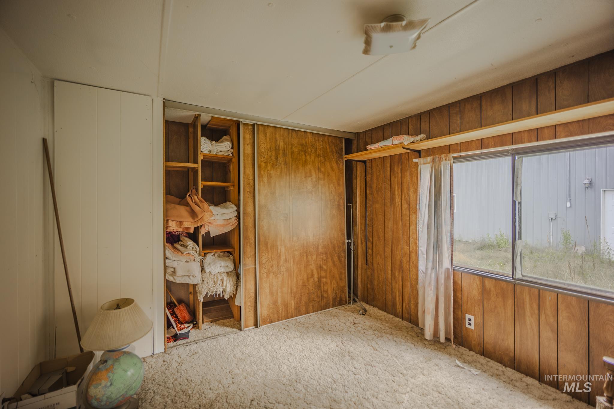 Unfurnished room featuring wood walls and carpet