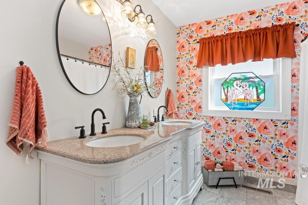 Bathroom featuring double vanity and wallpapered walls