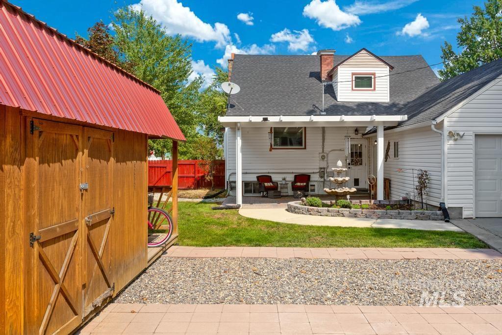 Rear view of property featuring roof with shingles, a storage shed, a chimney, and a garage