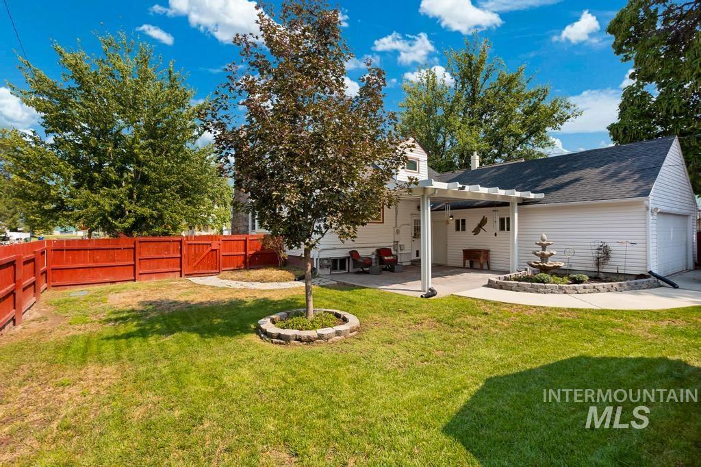 Back of house with a pergola, an attached garage, a fenced backyard, and a patio area