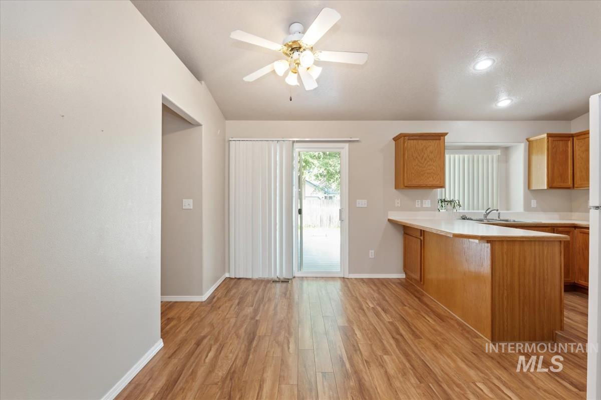 Kitchen with light countertops, a peninsula, light wood-type flooring, brown cabinets, and recessed lighting