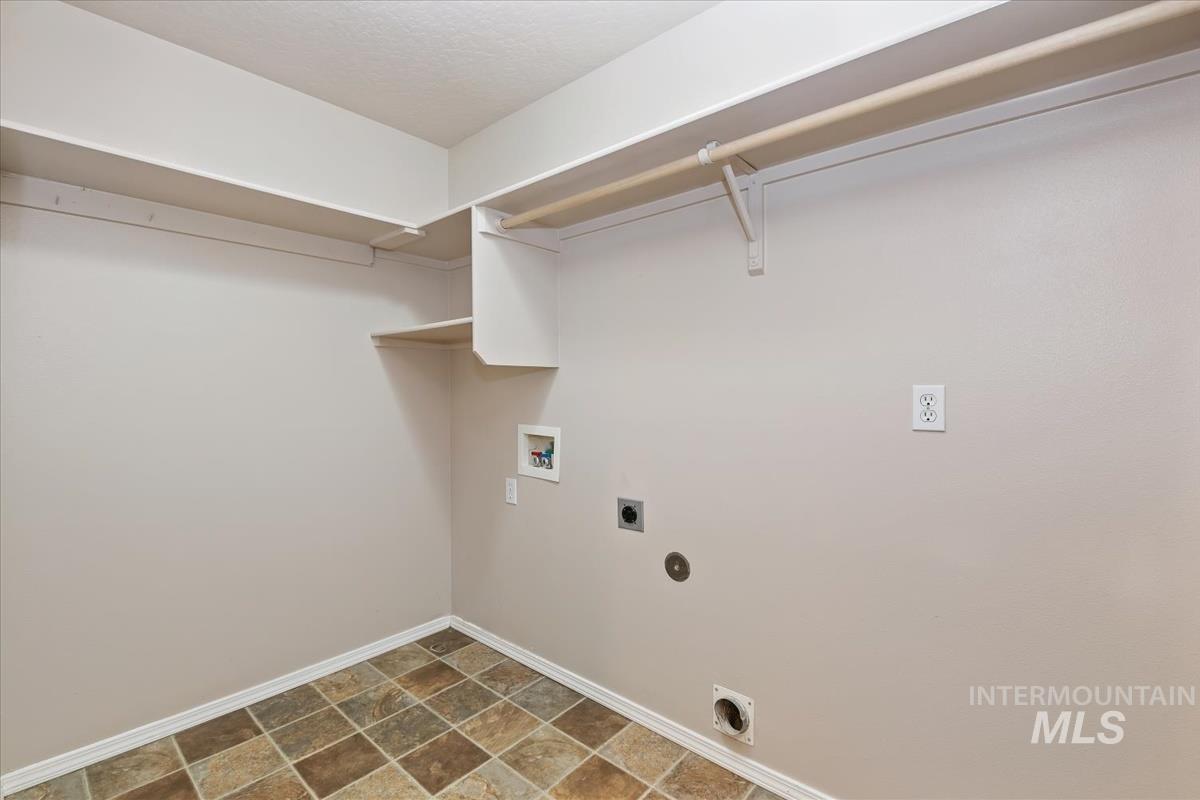 Washroom with hookup for a washing machine, hookup for an electric dryer, and stone finish floors