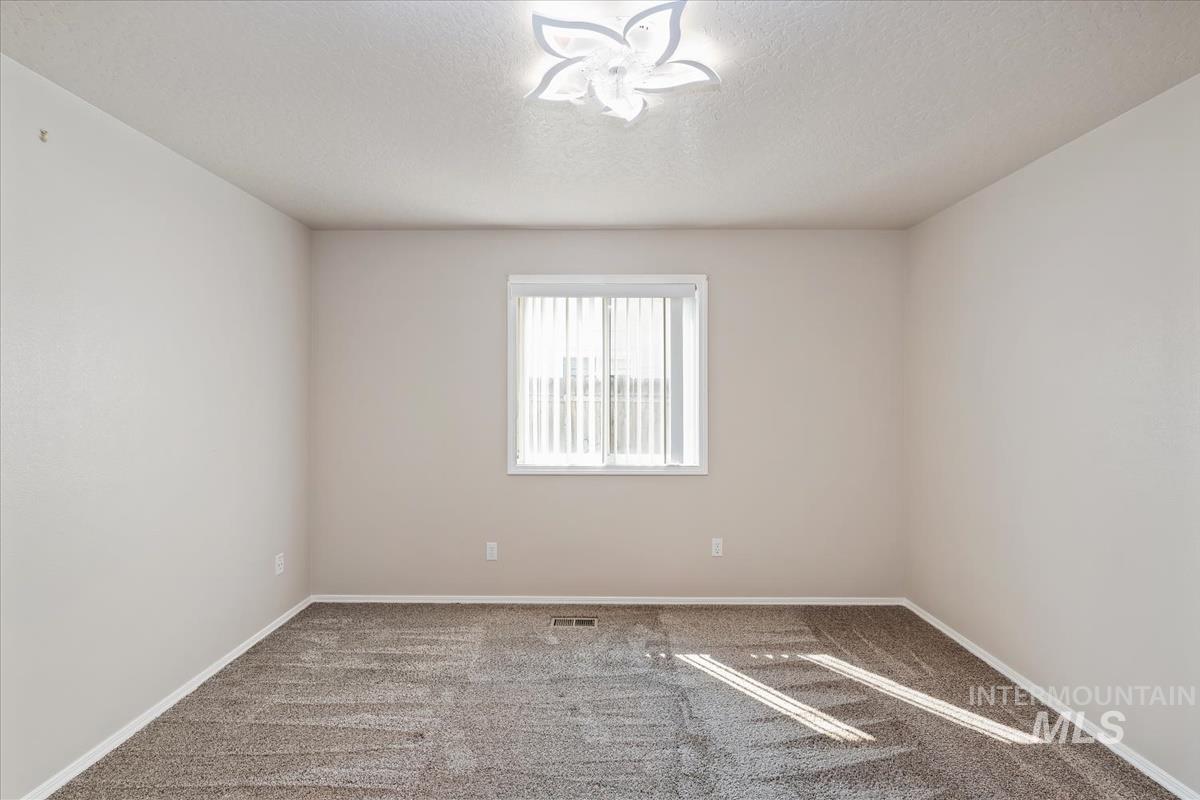 Carpeted spare room featuring baseboards and a textured ceiling