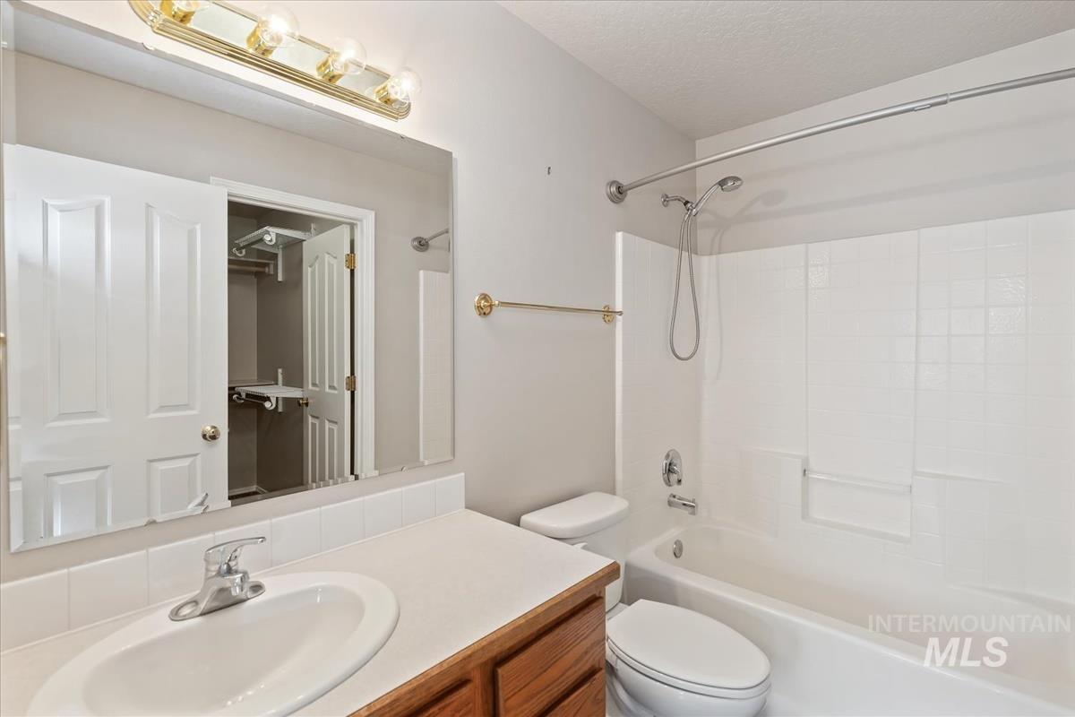 Full bath with washtub / shower combination, vanity, and a textured ceiling