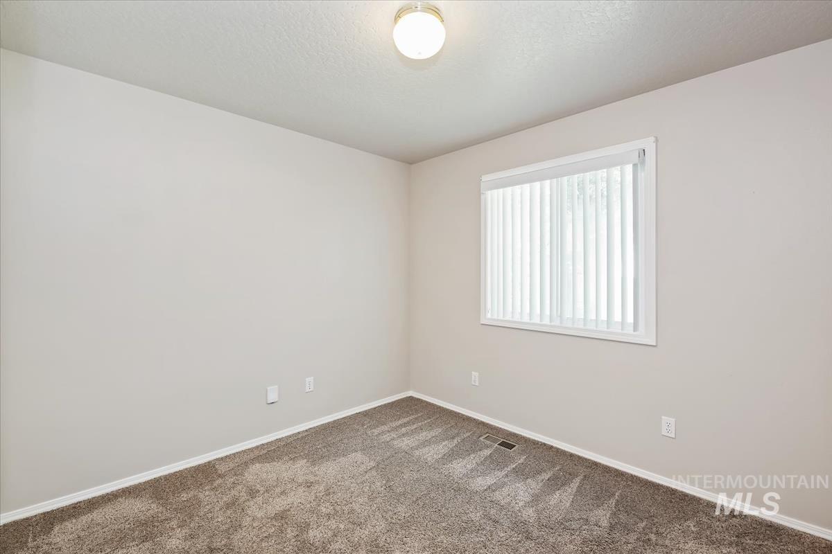 Empty room featuring carpet and a textured ceiling