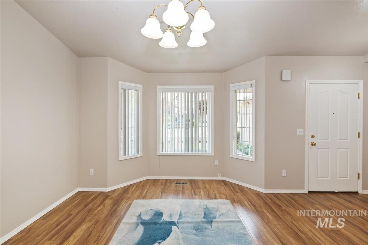 Unfurnished room featuring a chandelier and wood finished floors