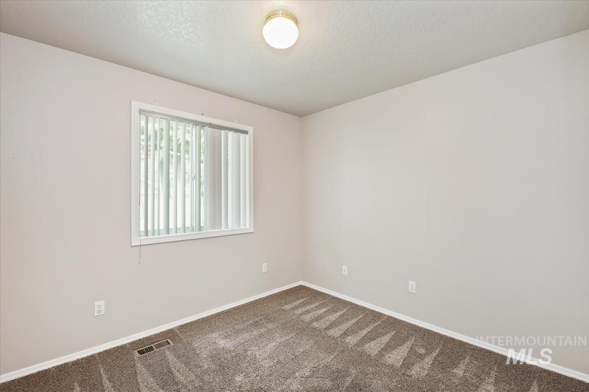 Unfurnished room with a textured ceiling and carpet flooring