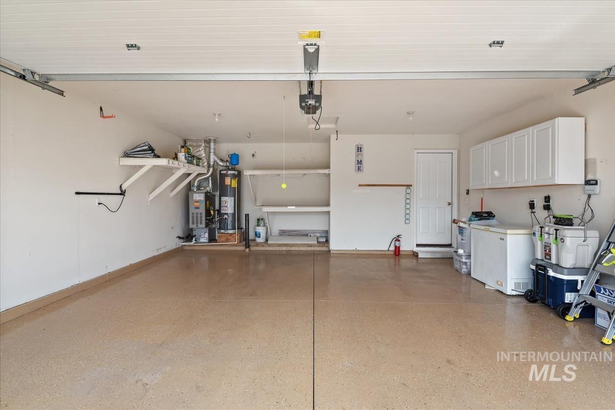 Garage with white fridge, gas water heater, and a garage door opener