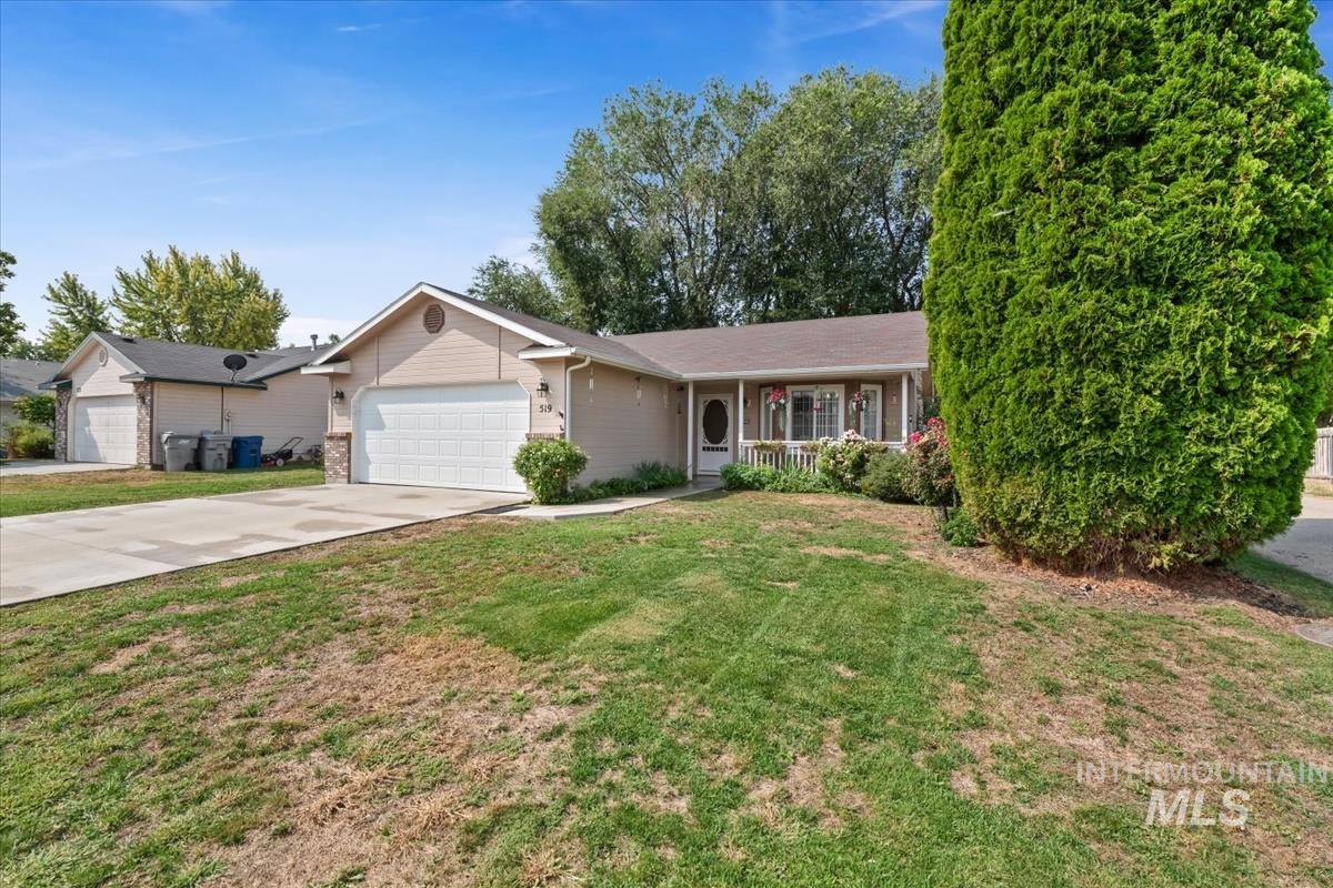 Ranch-style house featuring driveway, a front yard, an attached garage, and covered porch