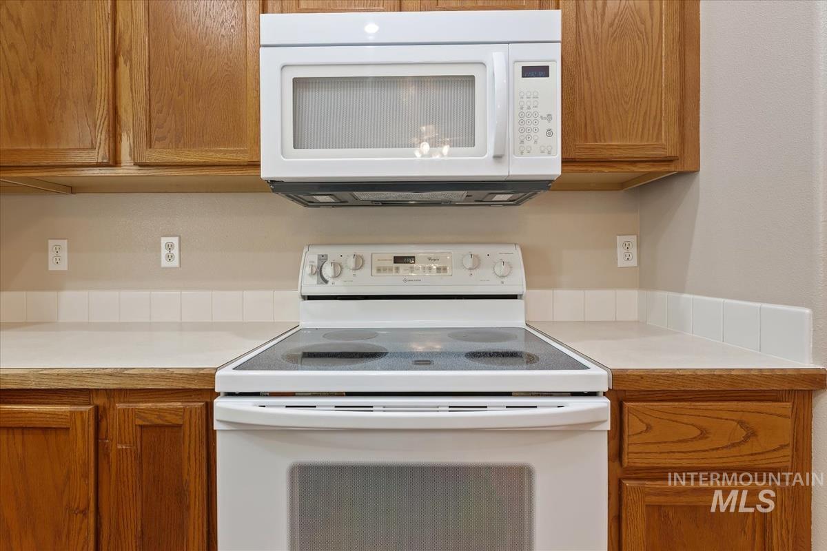 Kitchen featuring white appliances, brown cabinets, and light countertops