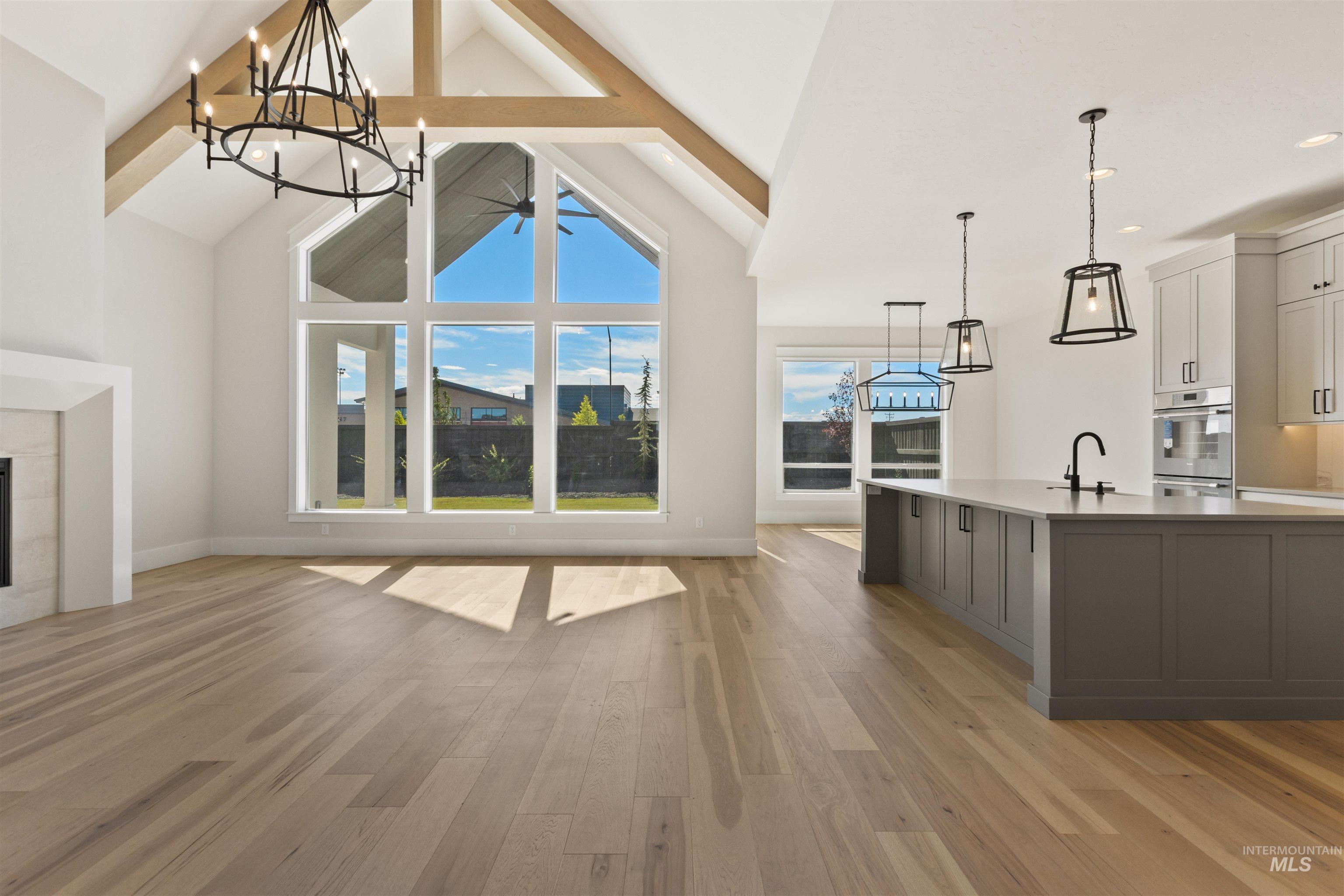 Unfurnished living room featuring a chandelier, beamed ceiling, light wood-style flooring, high vaulted ceiling, and recessed lighting
