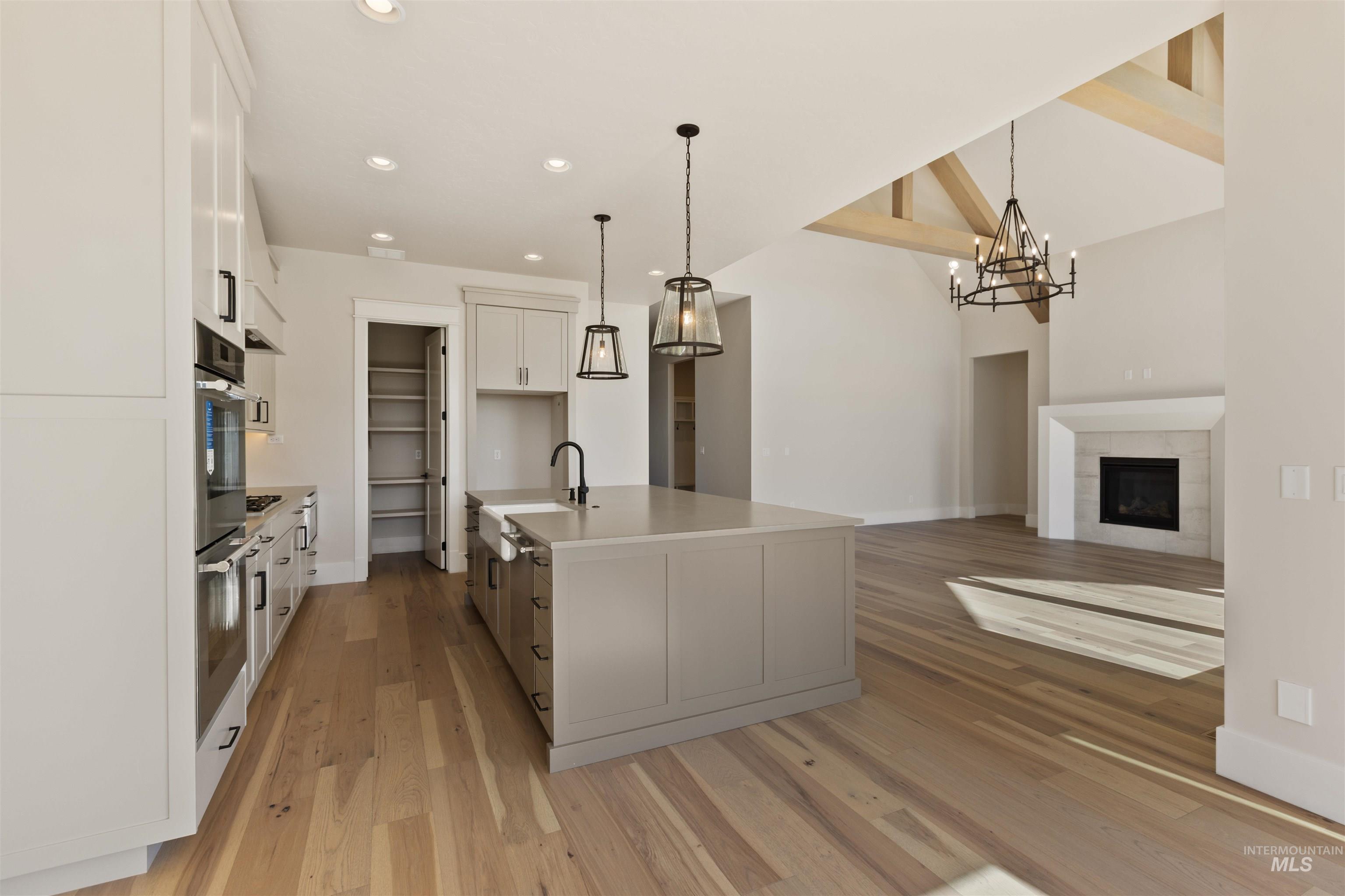 Kitchen with light wood finished floors, white cabinetry, a chandelier, recessed lighting, and hanging light fixtures