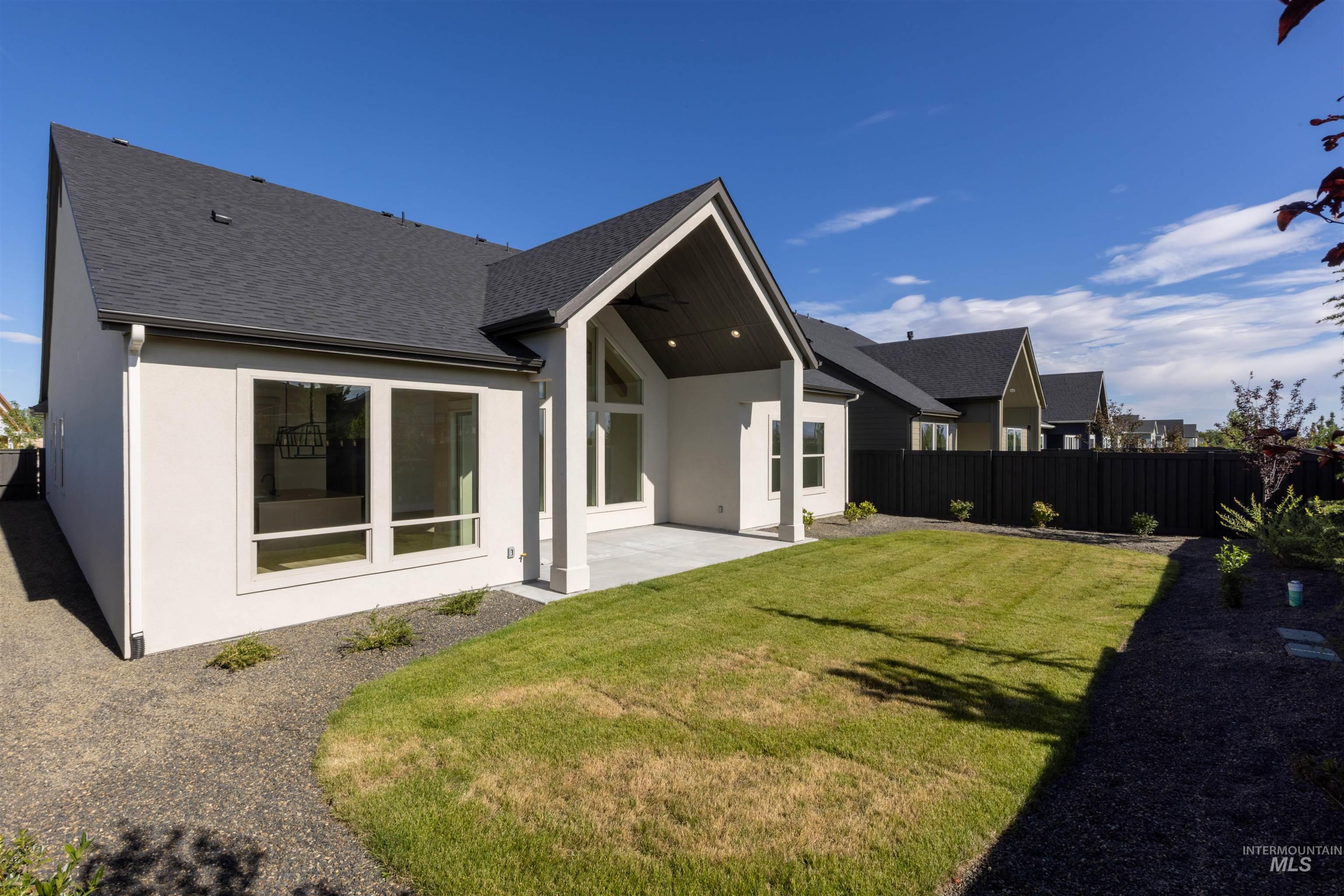Rear view of property featuring stucco siding, a patio area, roof with shingles, and ceiling fan