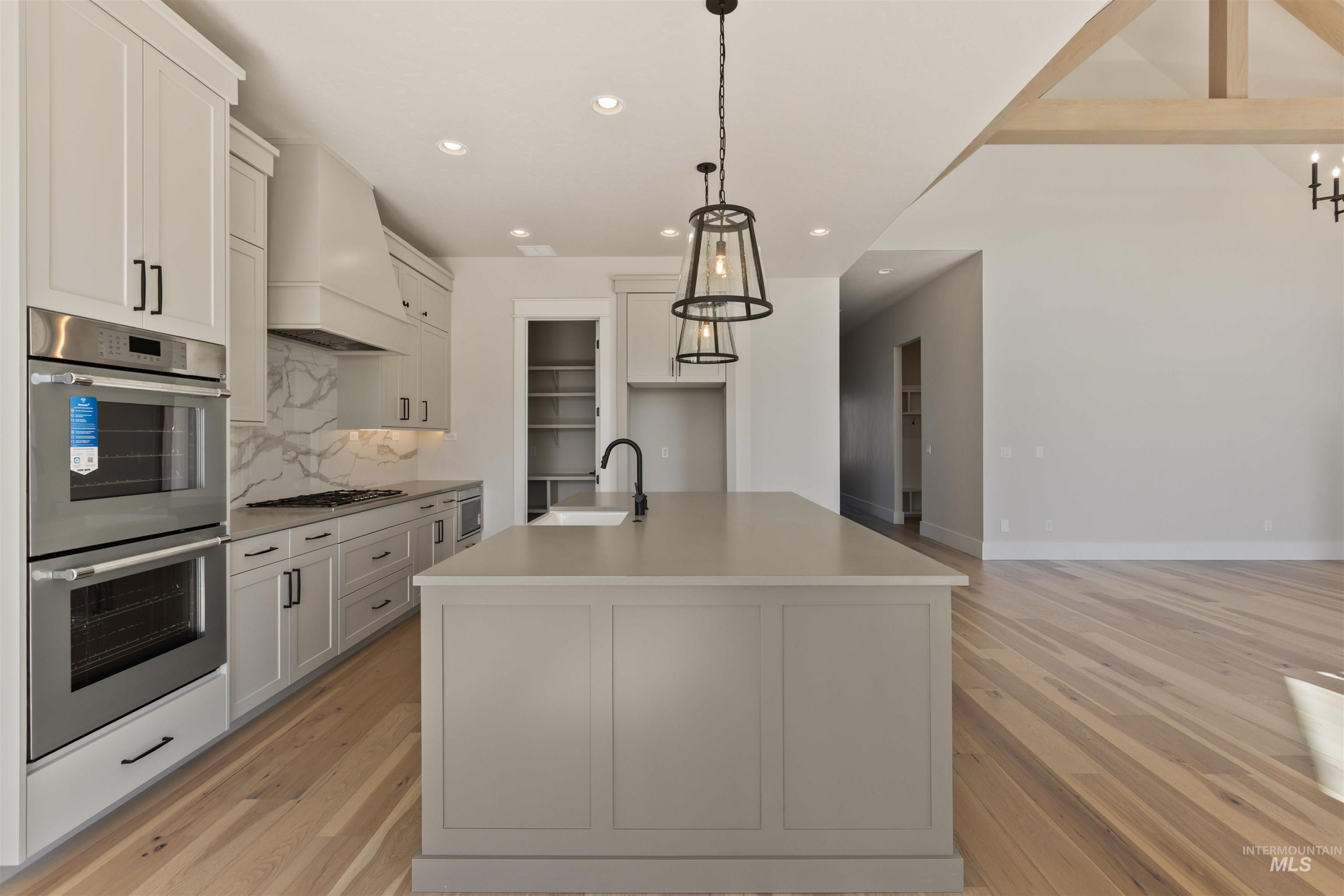 Kitchen with stainless steel appliances, recessed lighting, light wood-type flooring, tasteful backsplash, and custom exhaust hood