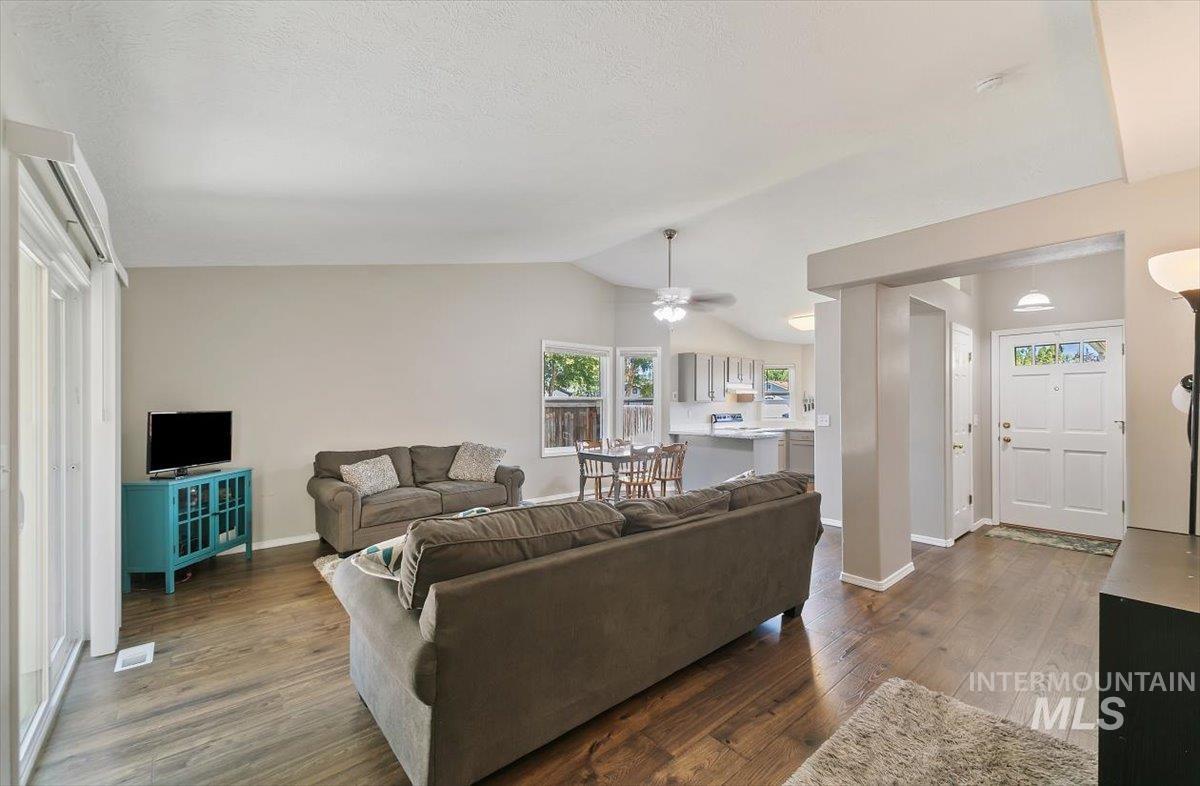 Living area with dark wood finished floors, lofted ceiling, and a ceiling fan