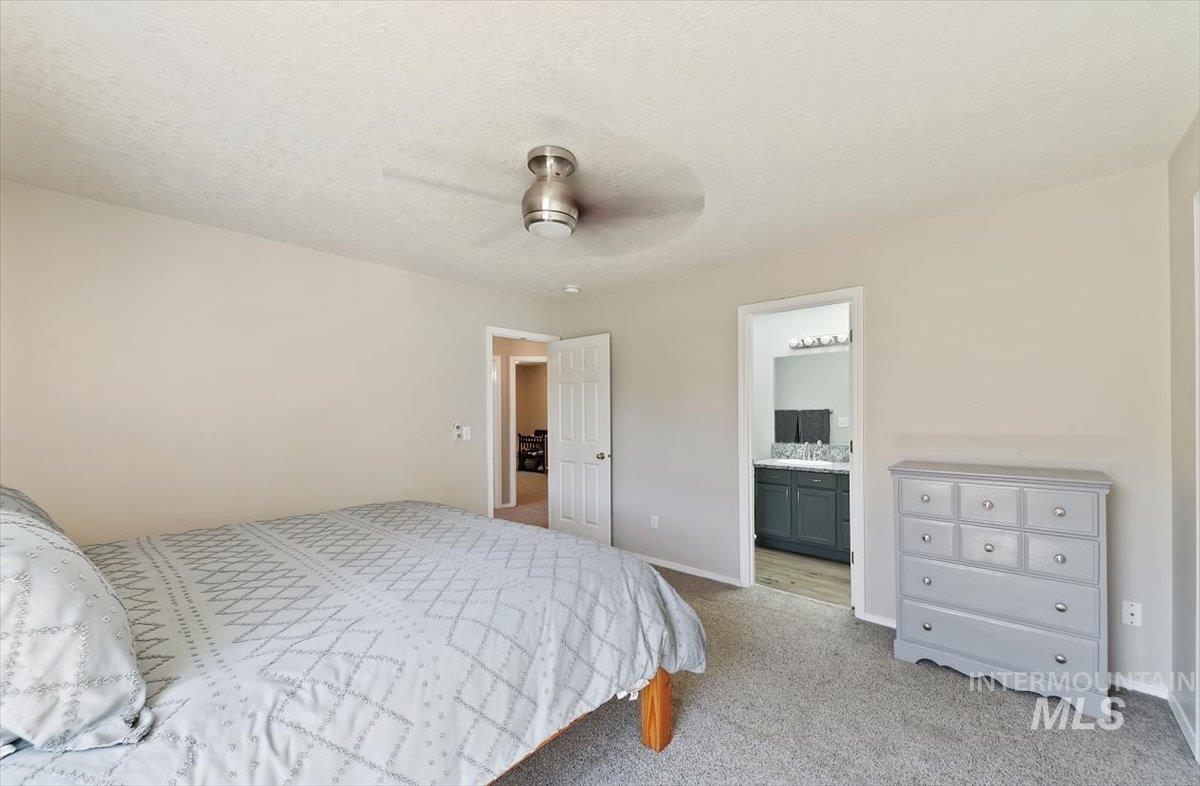 Bedroom featuring light carpet, a ceiling fan, a textured ceiling, and ensuite bathroom