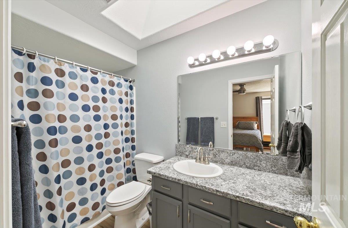 Ensuite bathroom featuring vanity, a shower with shower curtain, and ceiling fan