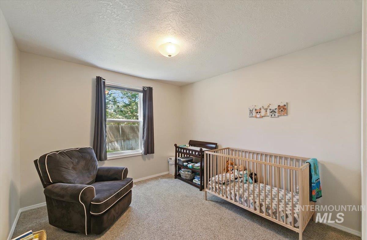 Carpeted bedroom with a crib and a textured ceiling