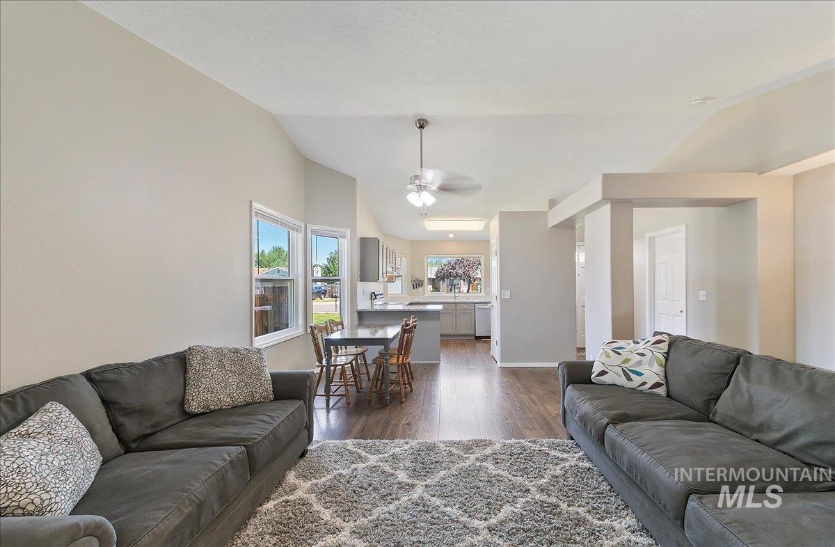 Living area featuring dark wood-type flooring, vaulted ceiling, and a ceiling fan