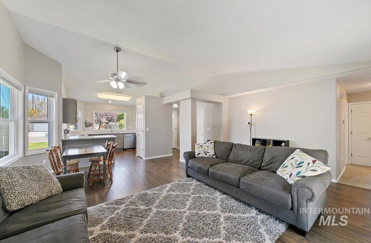 Living area featuring dark wood finished floors, vaulted ceiling, and a ceiling fan