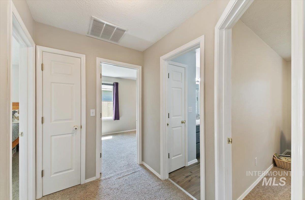 Hallway featuring carpet flooring and a textured ceiling
