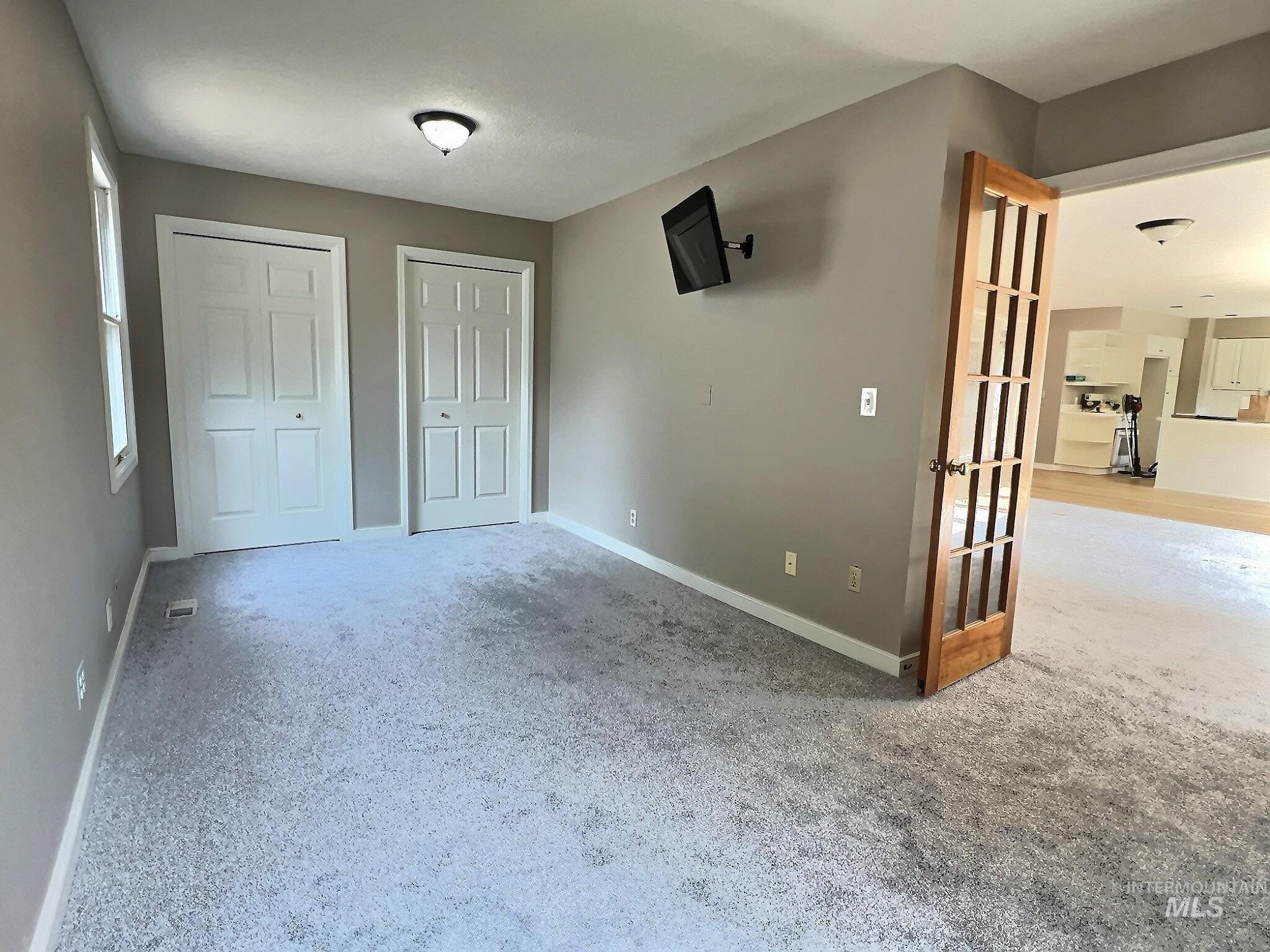Unfurnished bedroom with multiple closets and light colored carpet