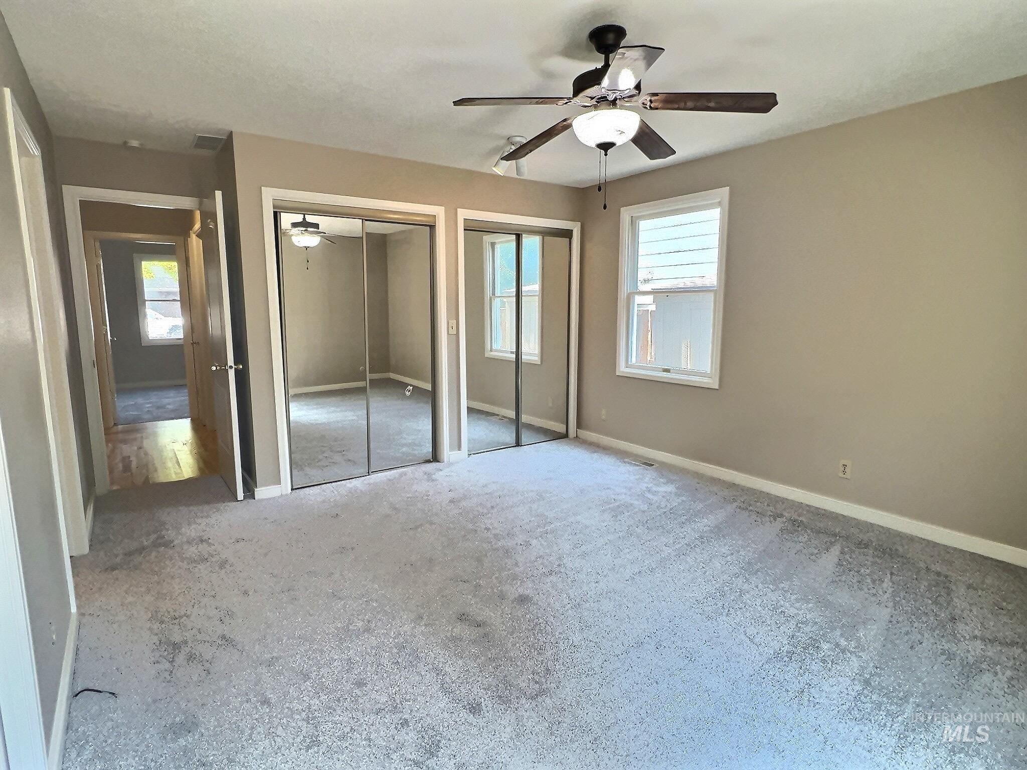 Unfurnished bedroom featuring multiple closets, carpet flooring, and ceiling fan