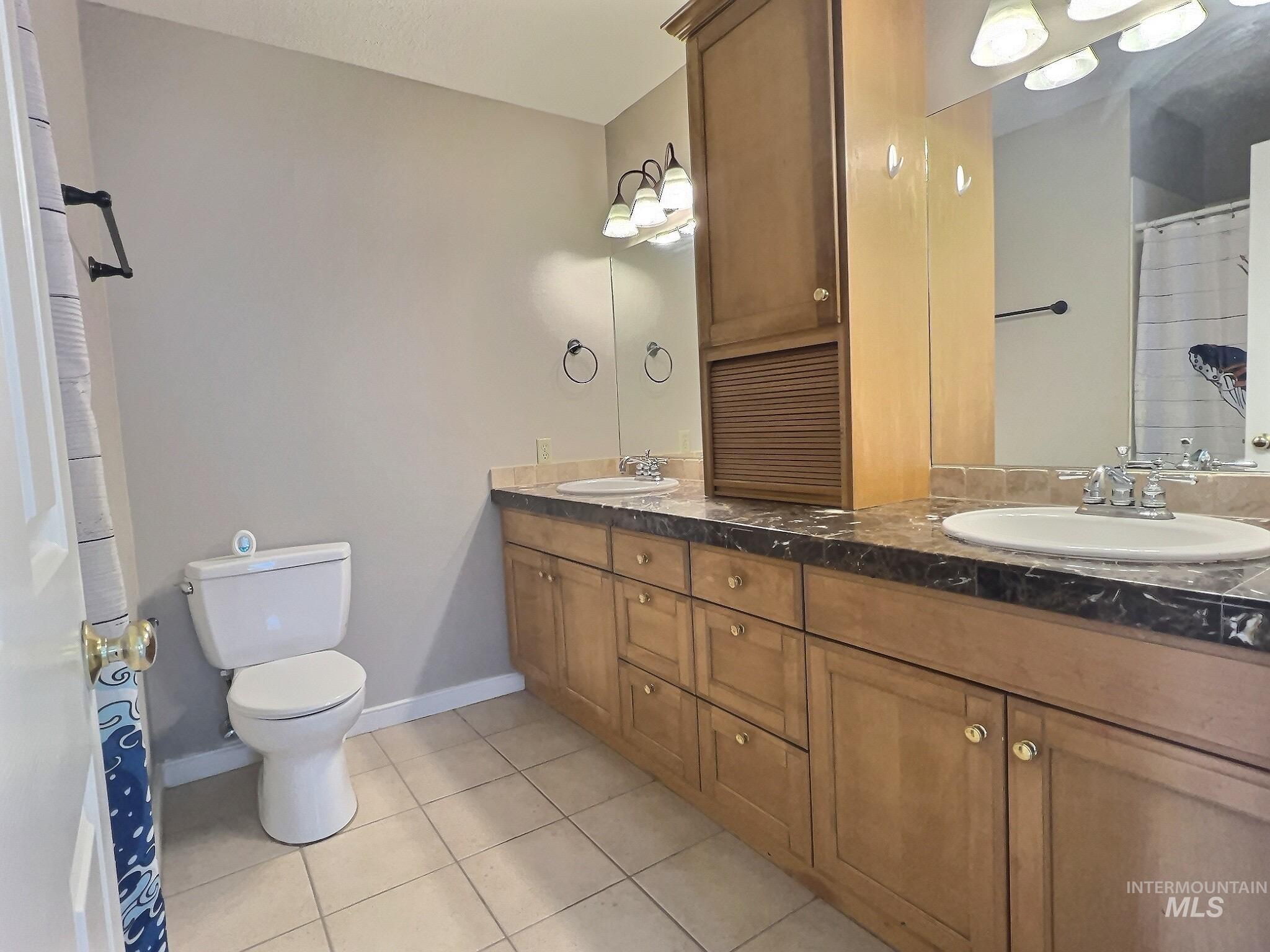 Full bath featuring light tile patterned floors, double vanity, and a shower with curtain