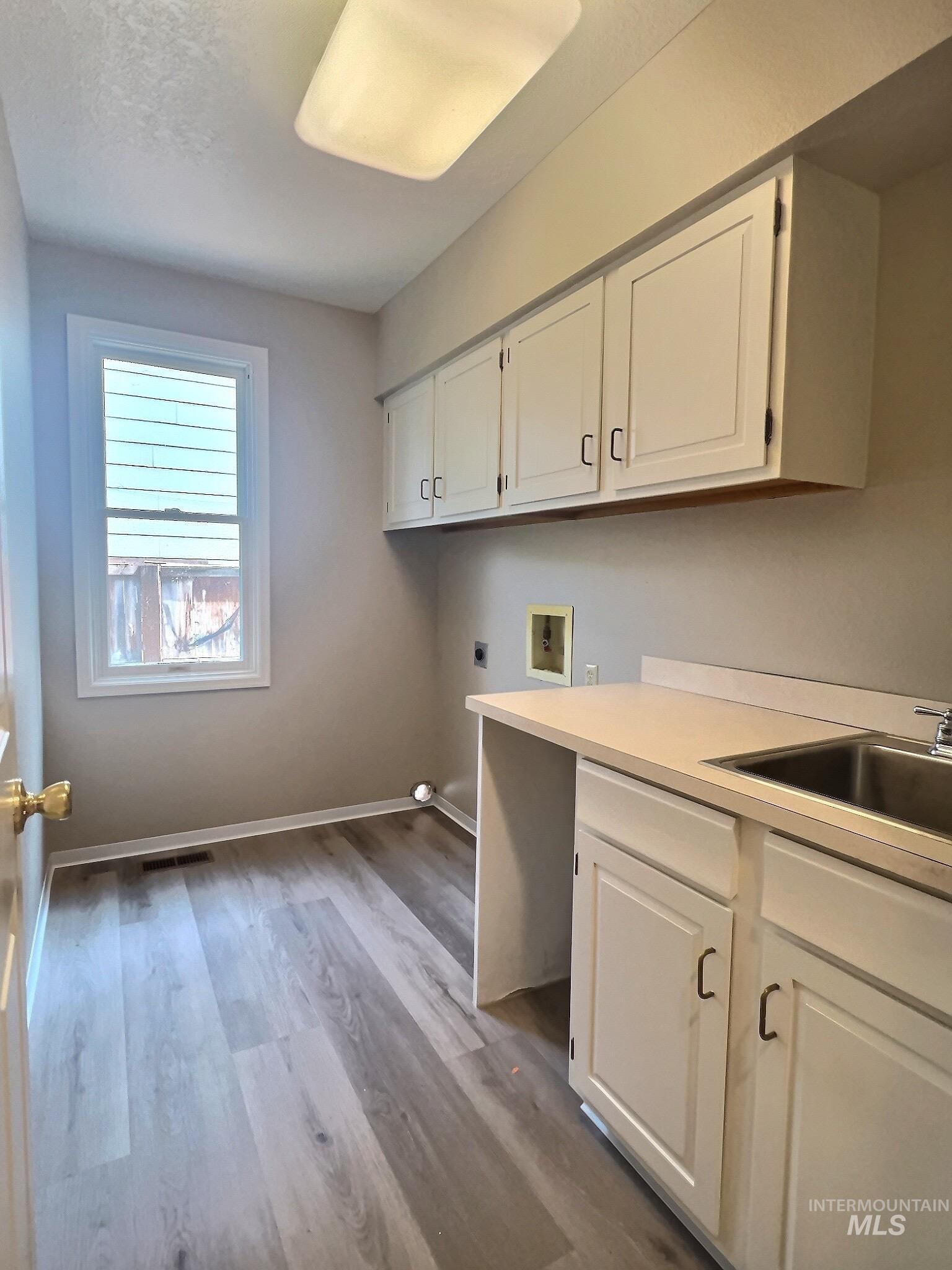 Laundry room featuring hookup for a washing machine, hookup for an electric dryer, light wood finished floors, and cabinet space