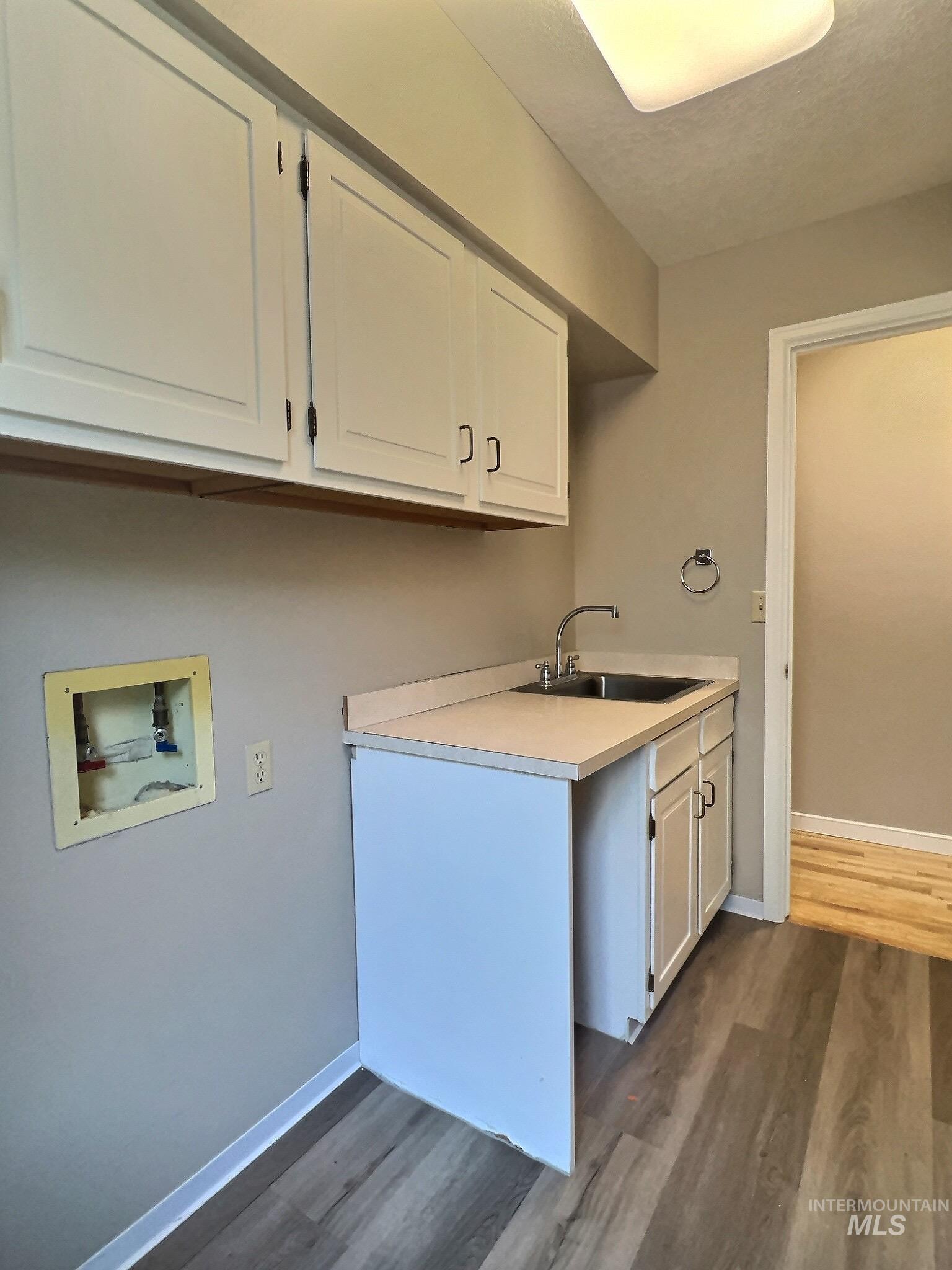 Laundry room with cabinet space, hookup for a washing machine, dark wood-style flooring, and a textured ceiling
