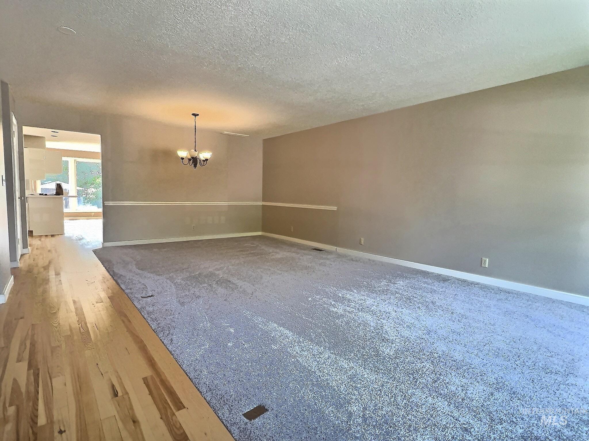 Unfurnished room with wood-type flooring, a textured ceiling, and a chandelier