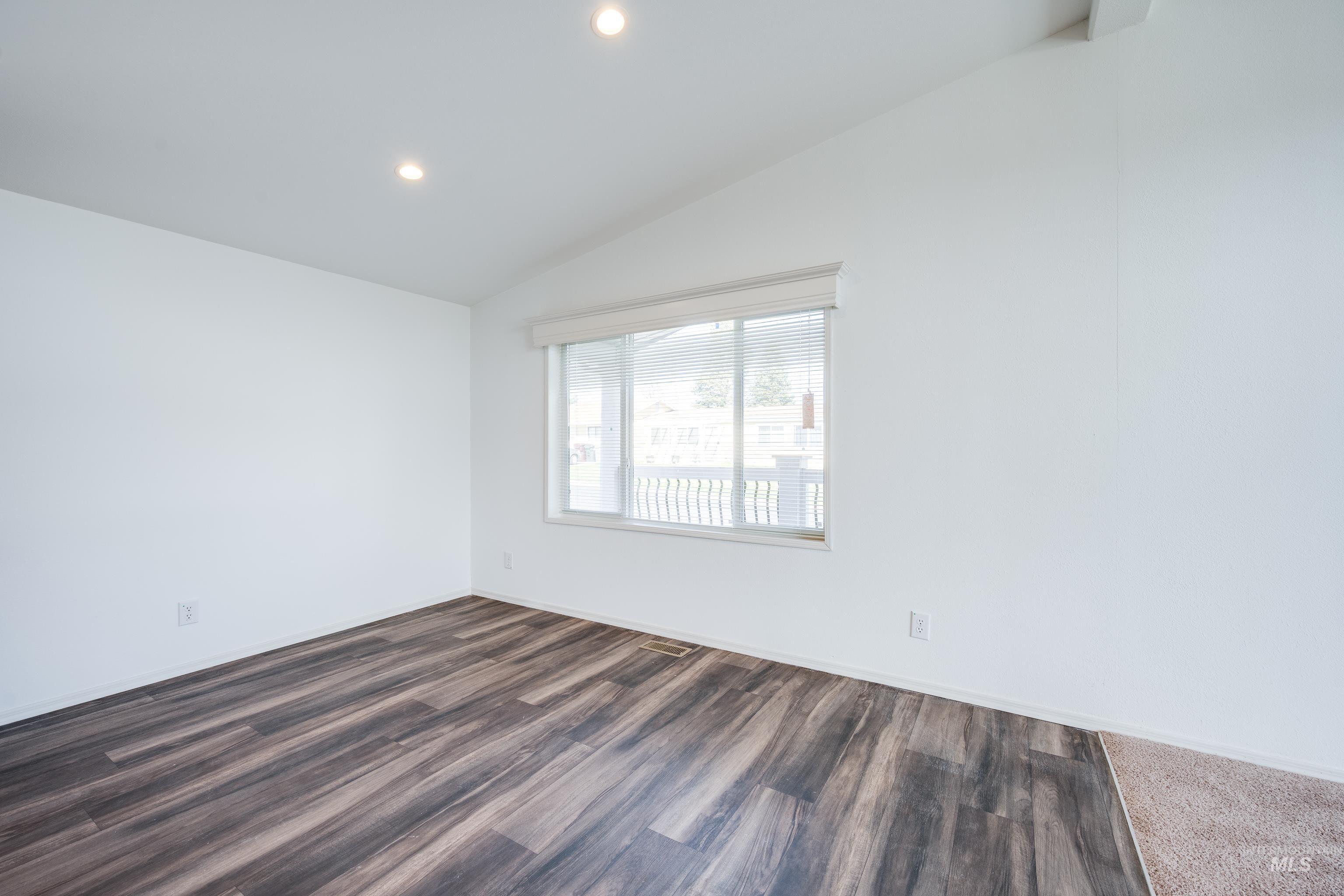 Spare room with vaulted ceiling, dark wood-style flooring, and recessed lighting