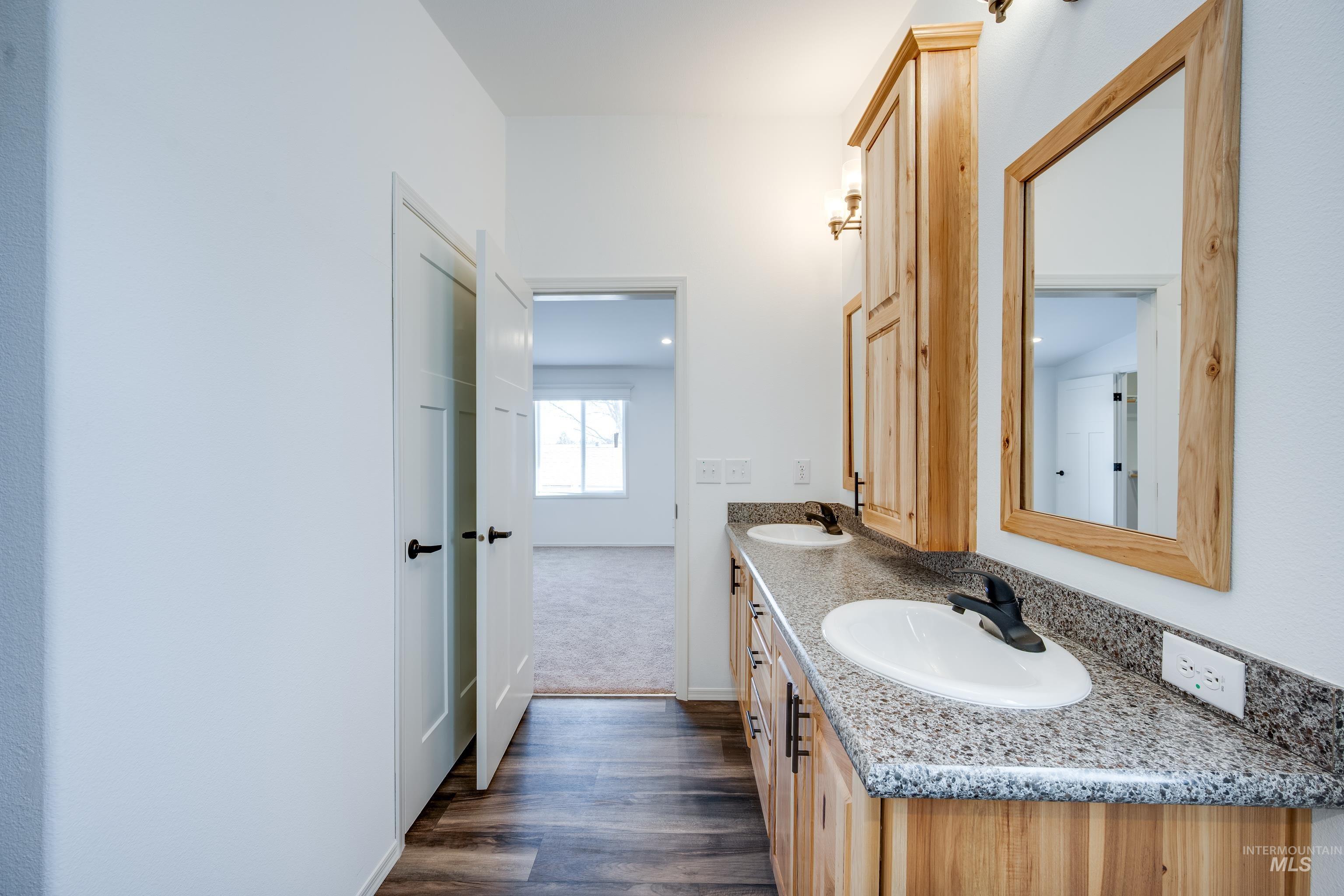 Full bath with double vanity and dark wood finished floors