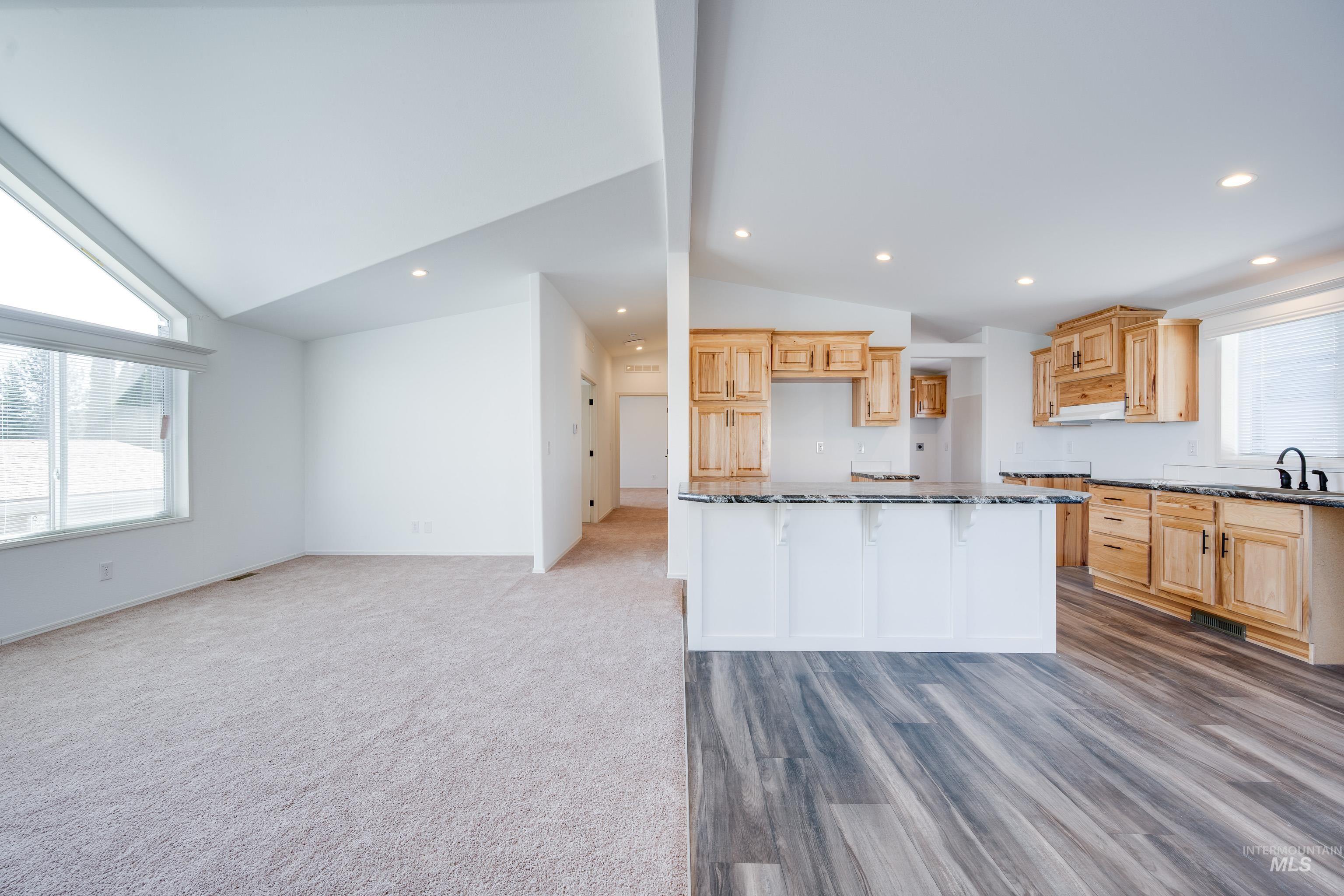 Kitchen with vaulted ceiling, open floor plan, a center island, recessed lighting, and light brown cabinetry