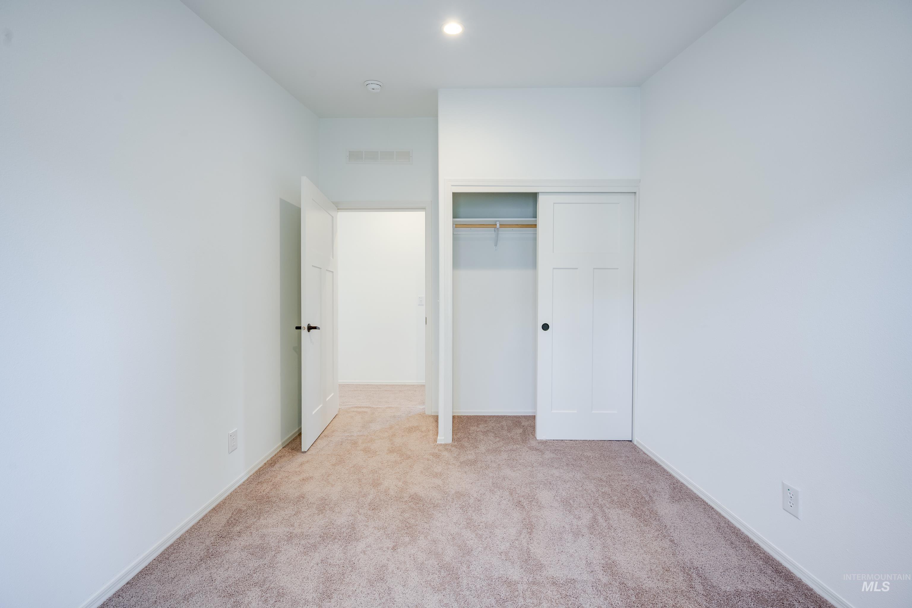 Unfurnished bedroom with light carpet and a closet