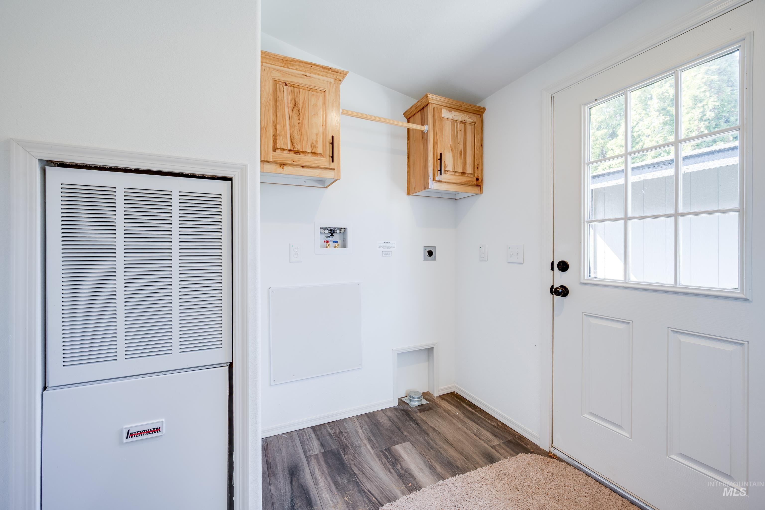 Laundry area featuring a heating unit, electric dryer hookup, dark wood-style floors, hookup for a washing machine, and cabinet space