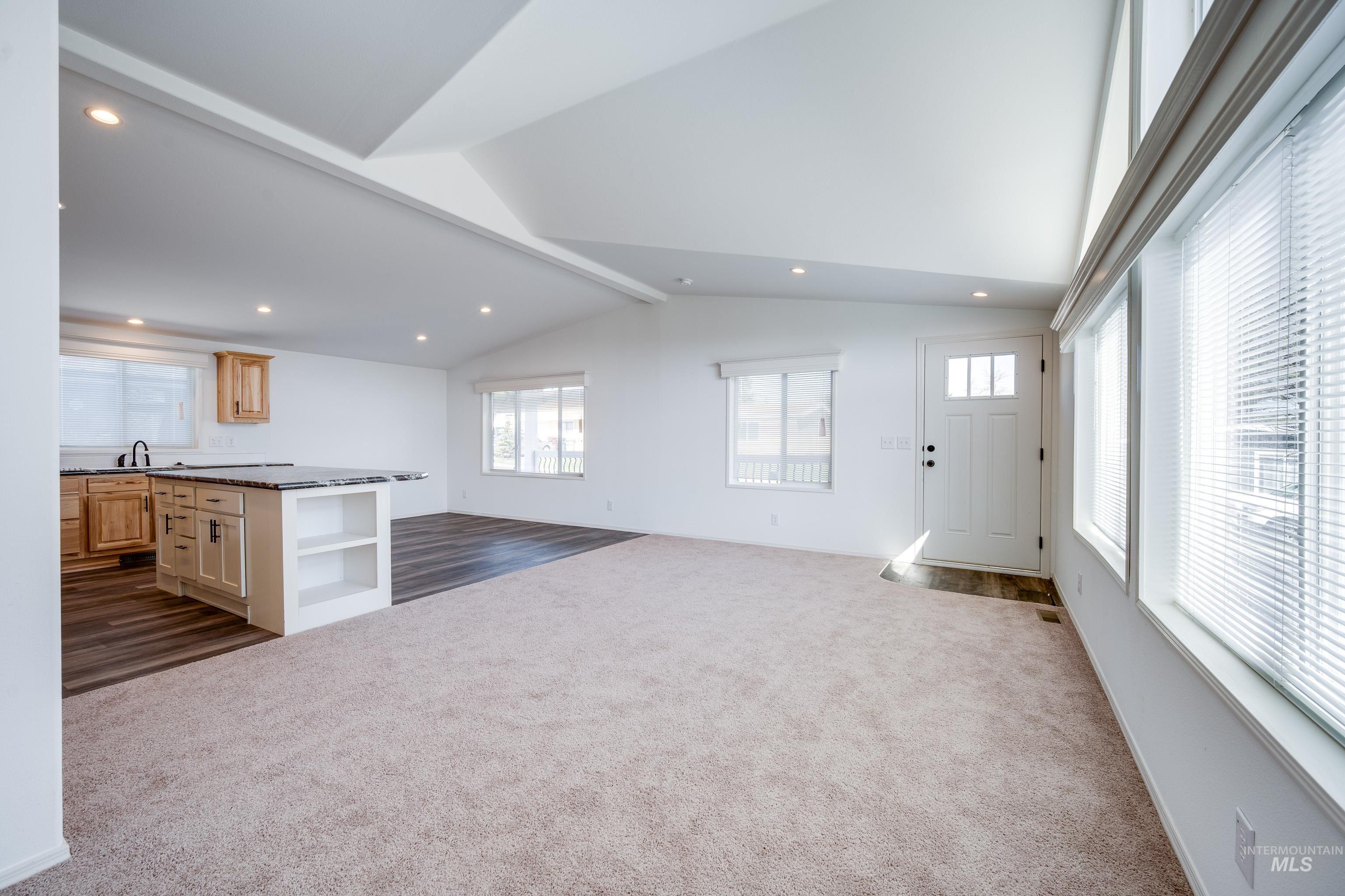Unfurnished living room with dark colored carpet, recessed lighting, and dark wood-style flooring
